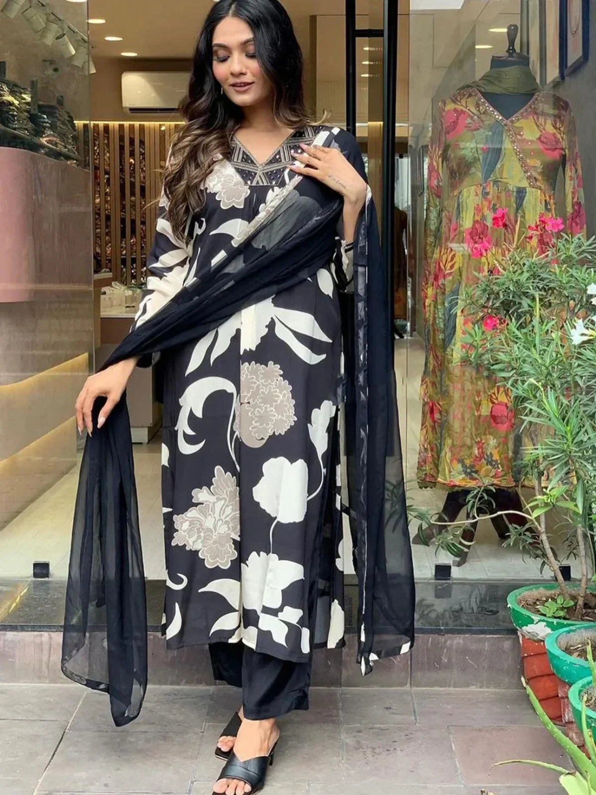 Woman wearing black and white floral salwar kameez with matching dupatta, standing outside shop