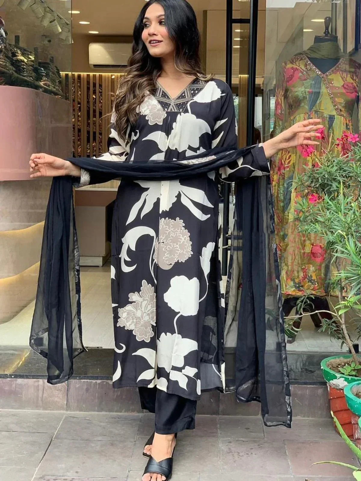 Woman wearing black and white floral printed salwar kameez with dupatta, standing outside store