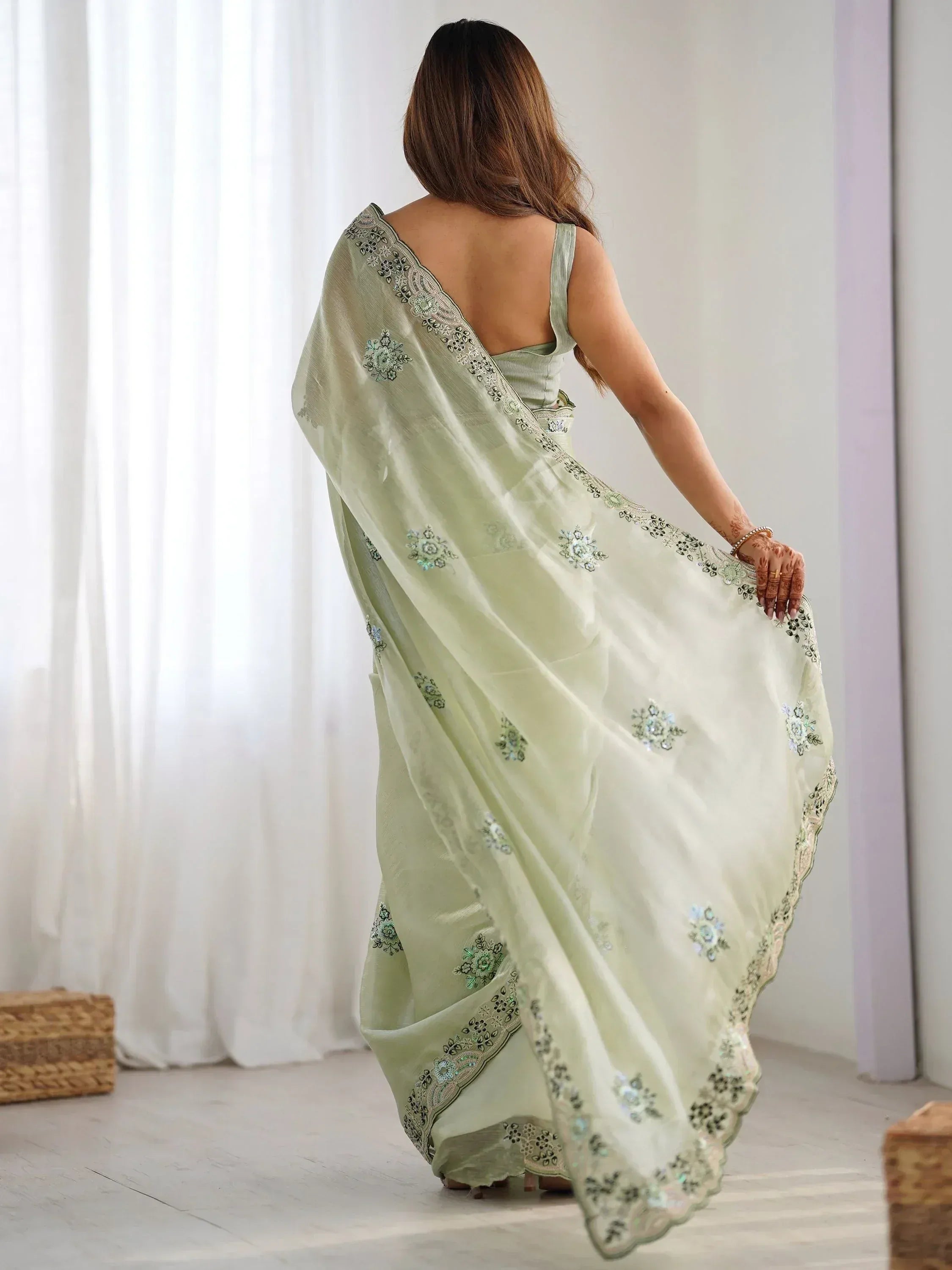 Light green embroidered saree with floral motifs and scalloped border, styled with backless blouse