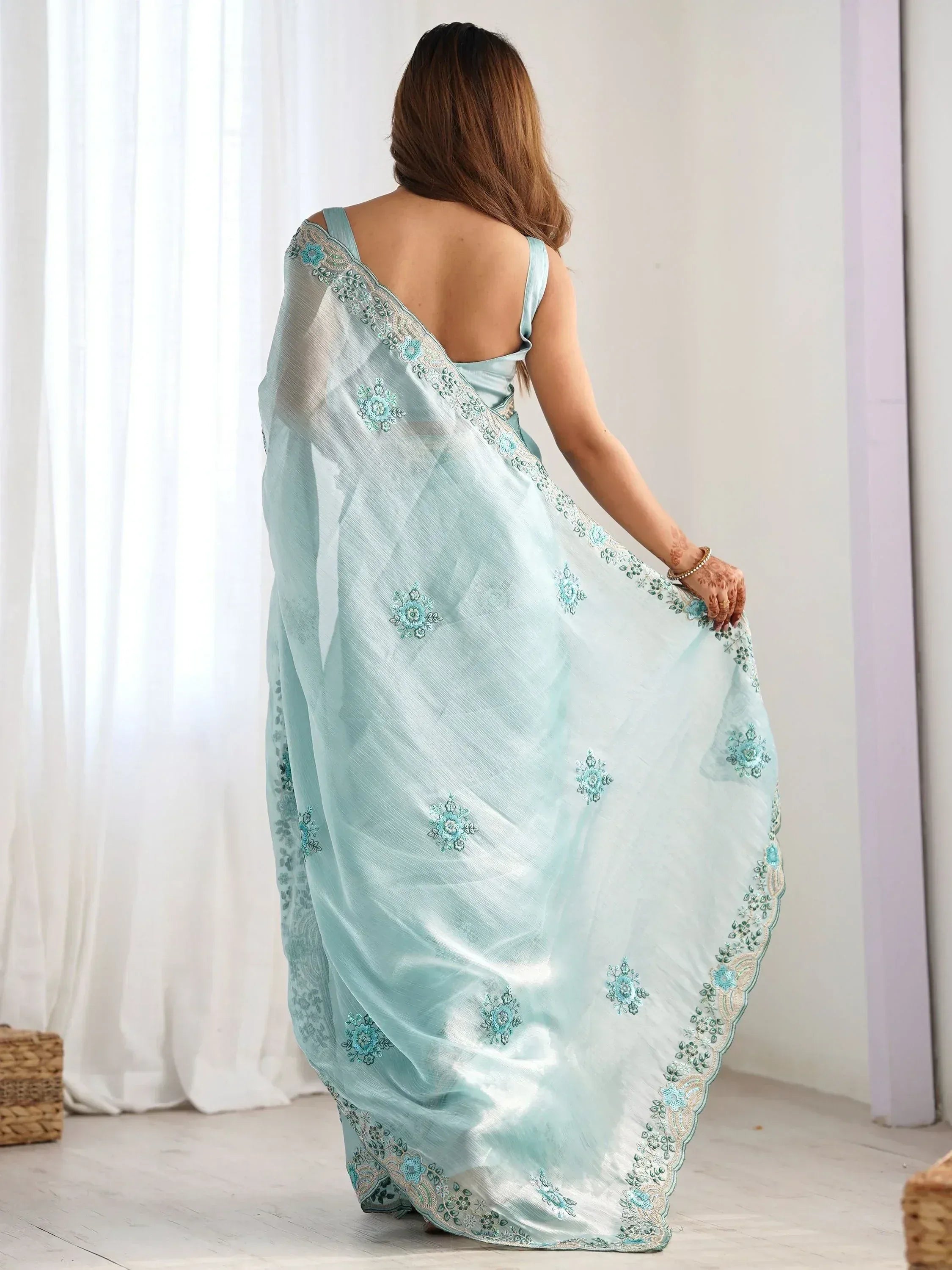 Light blue embroidered saree with floral motifs and scalloped border, worn with backless blouse