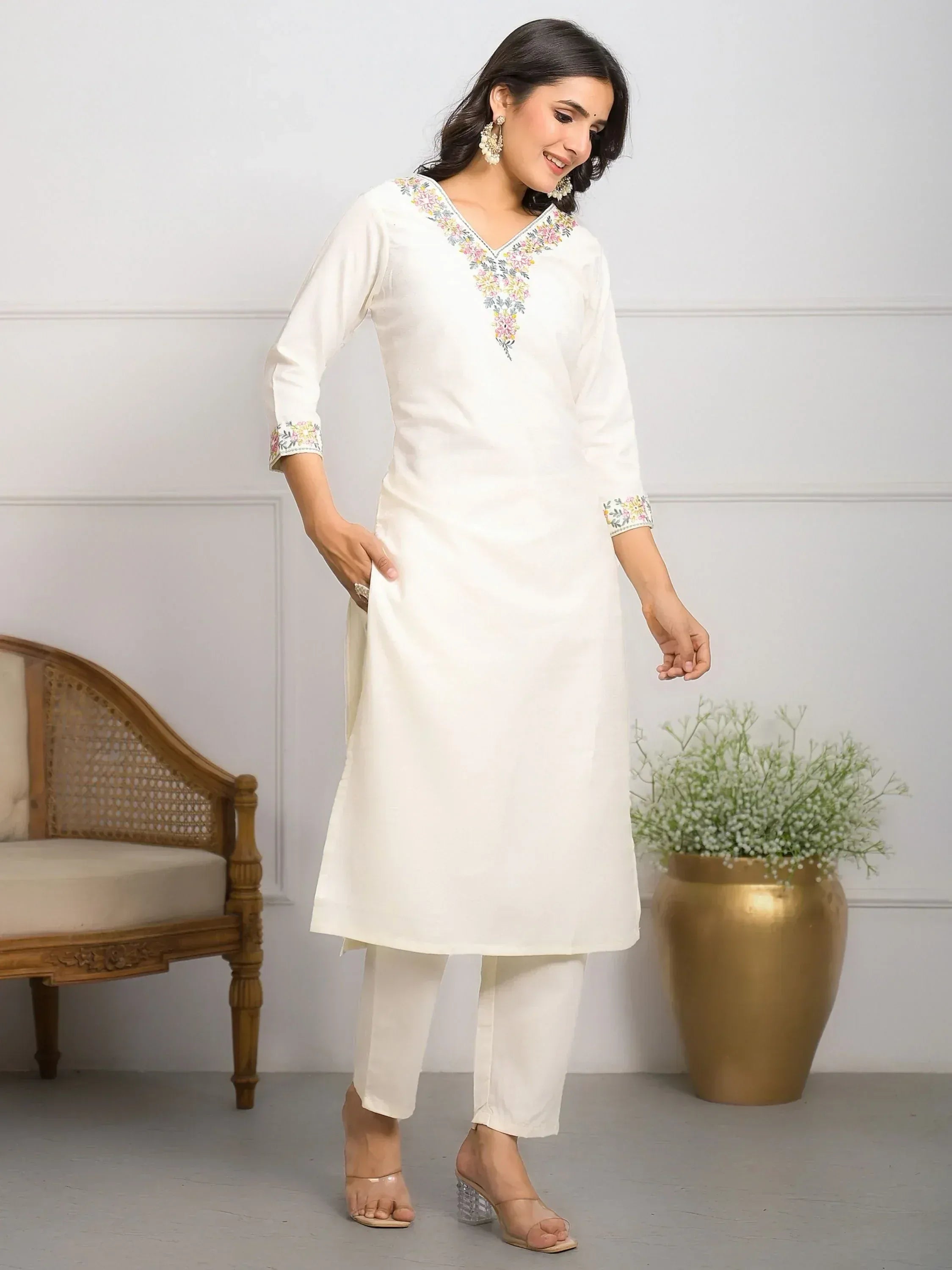 White embroidered kurta with floral neckline and sleeve details, paired with matching pants for ethnic wear.