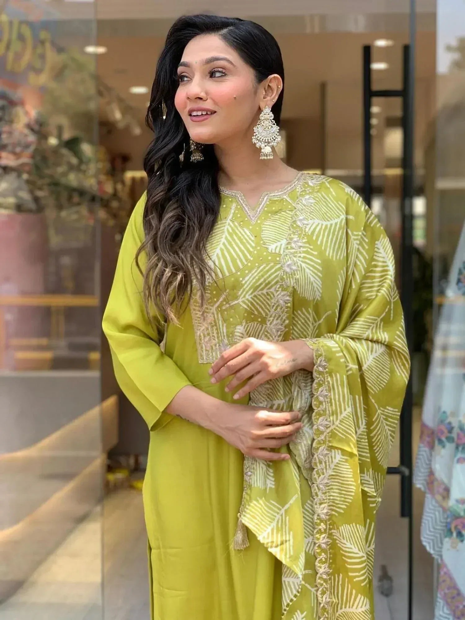 Woman in vibrant green ethnic kurta with white leaf print and embroidery, paired with statement earrings