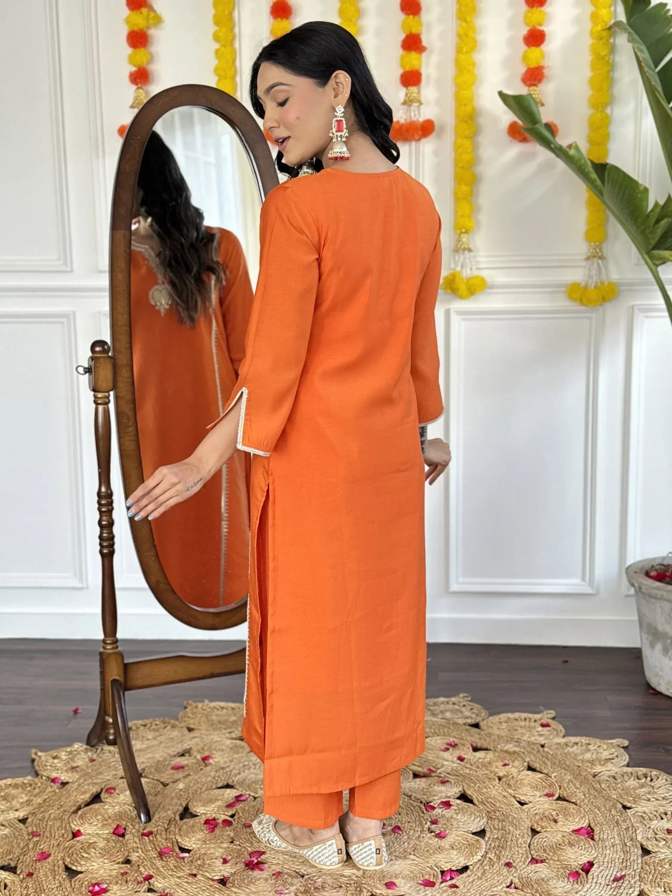 Orange ethnic kurta set with mirror reflection, festive decor, and traditional jewelry for Indian wear
