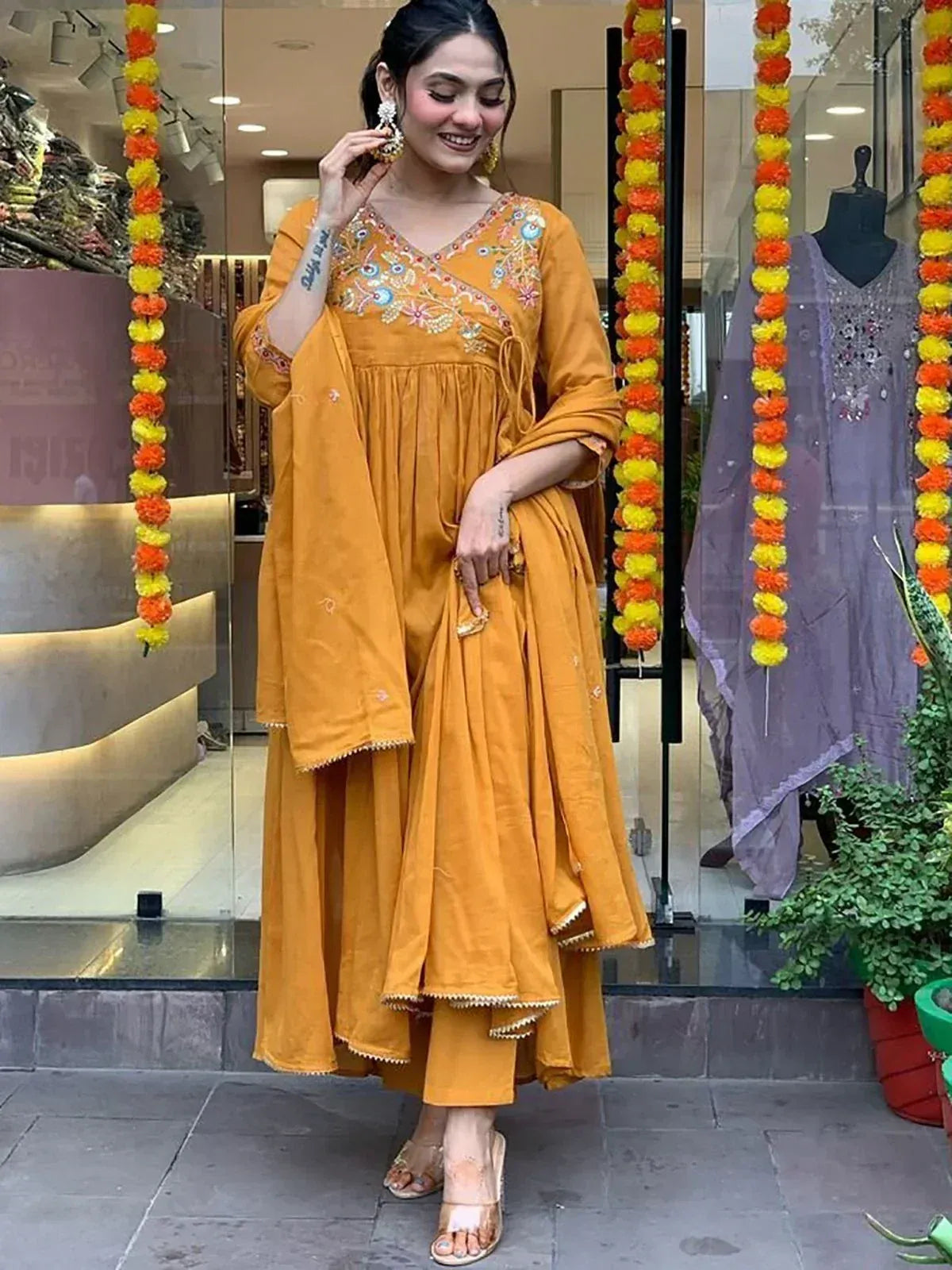 Woman in mustard yellow embroidered ethnic salwar kameez with floral garlands, perfect for festive occasions