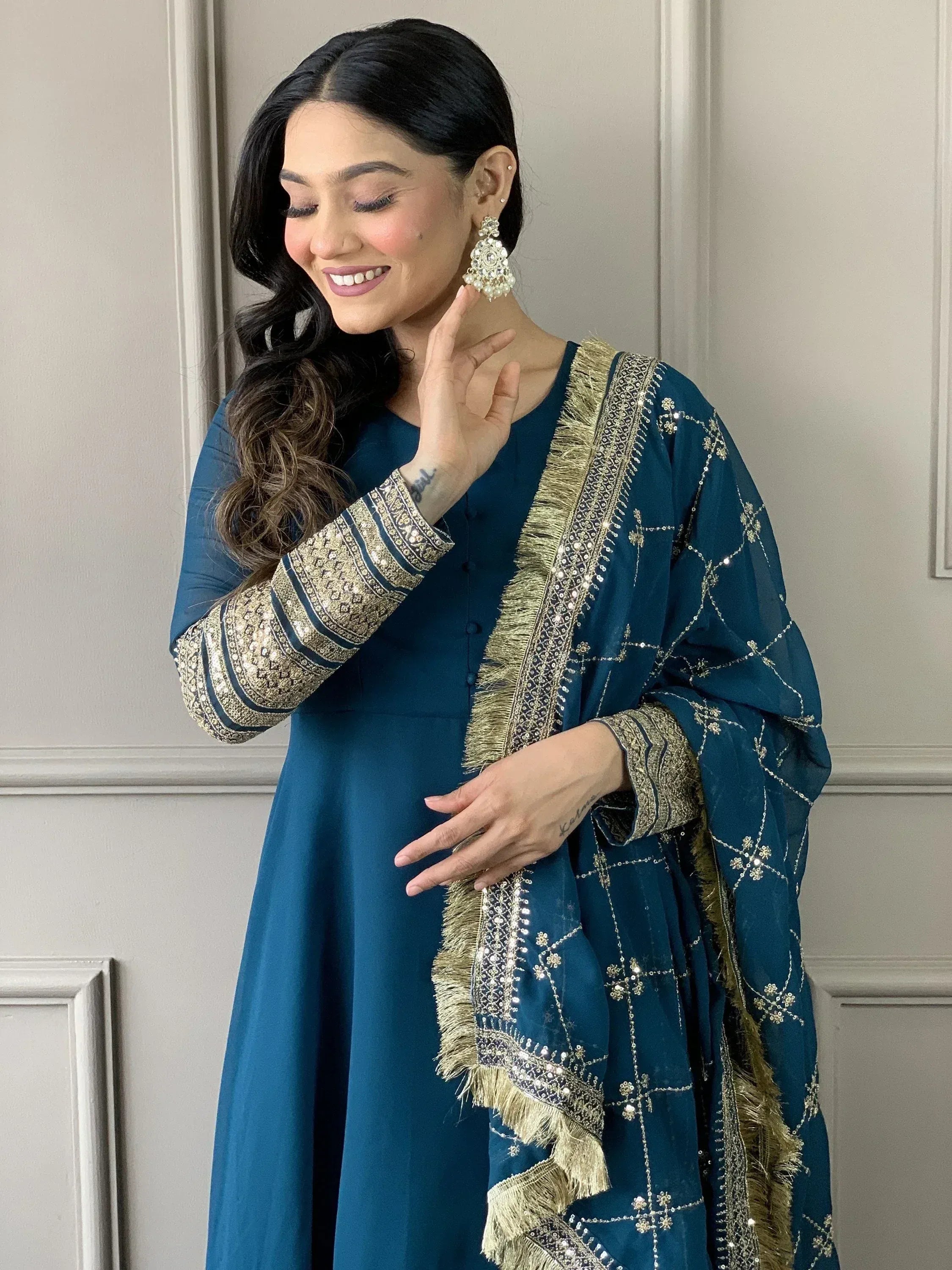 Teal Indian ethnic salwar kameez with gold embroidery and fringe dupatta, styled with statement earrings
