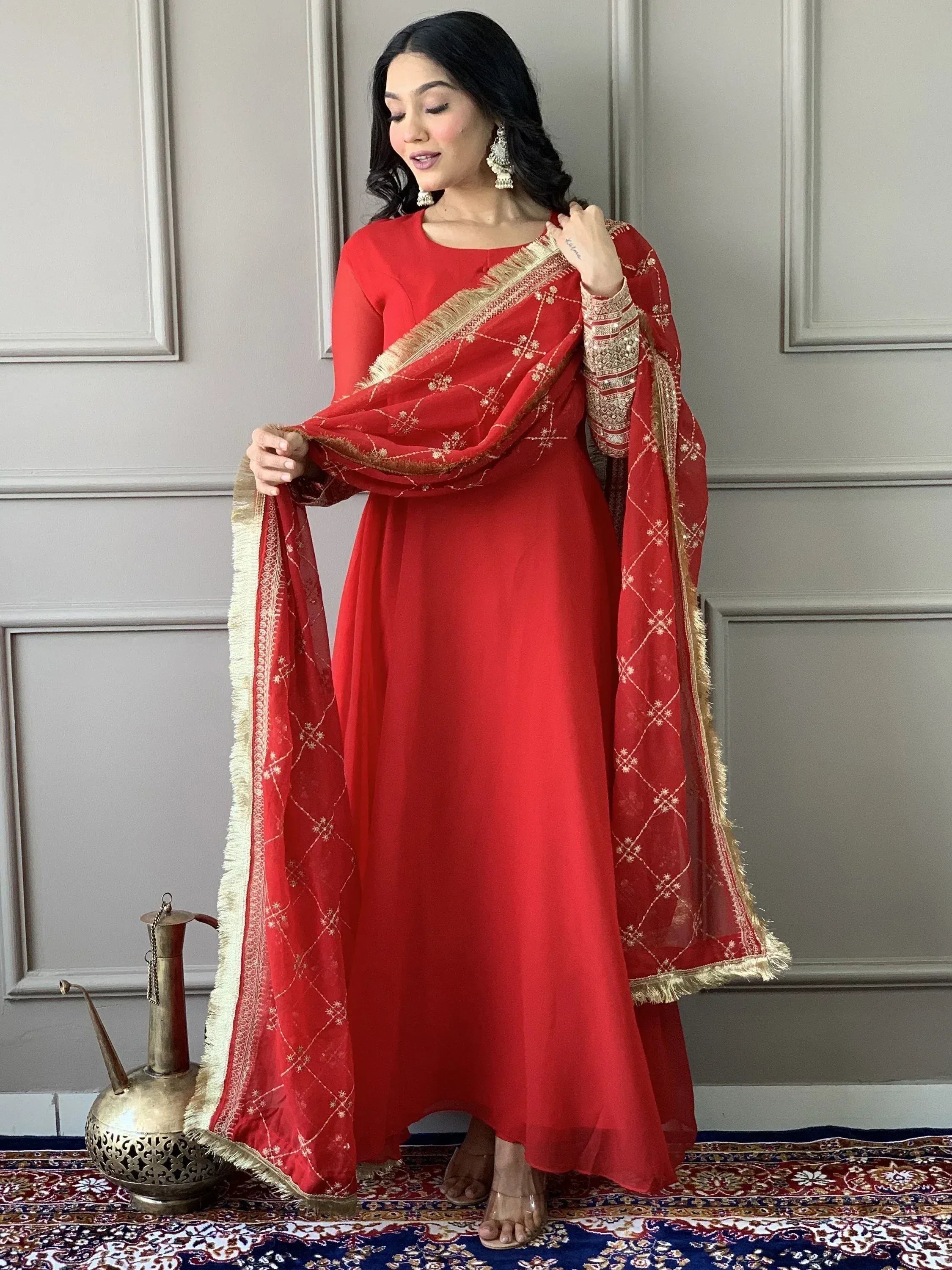 Red ethnic gown with gold embroidery and matching dupatta, styled for festive occasions