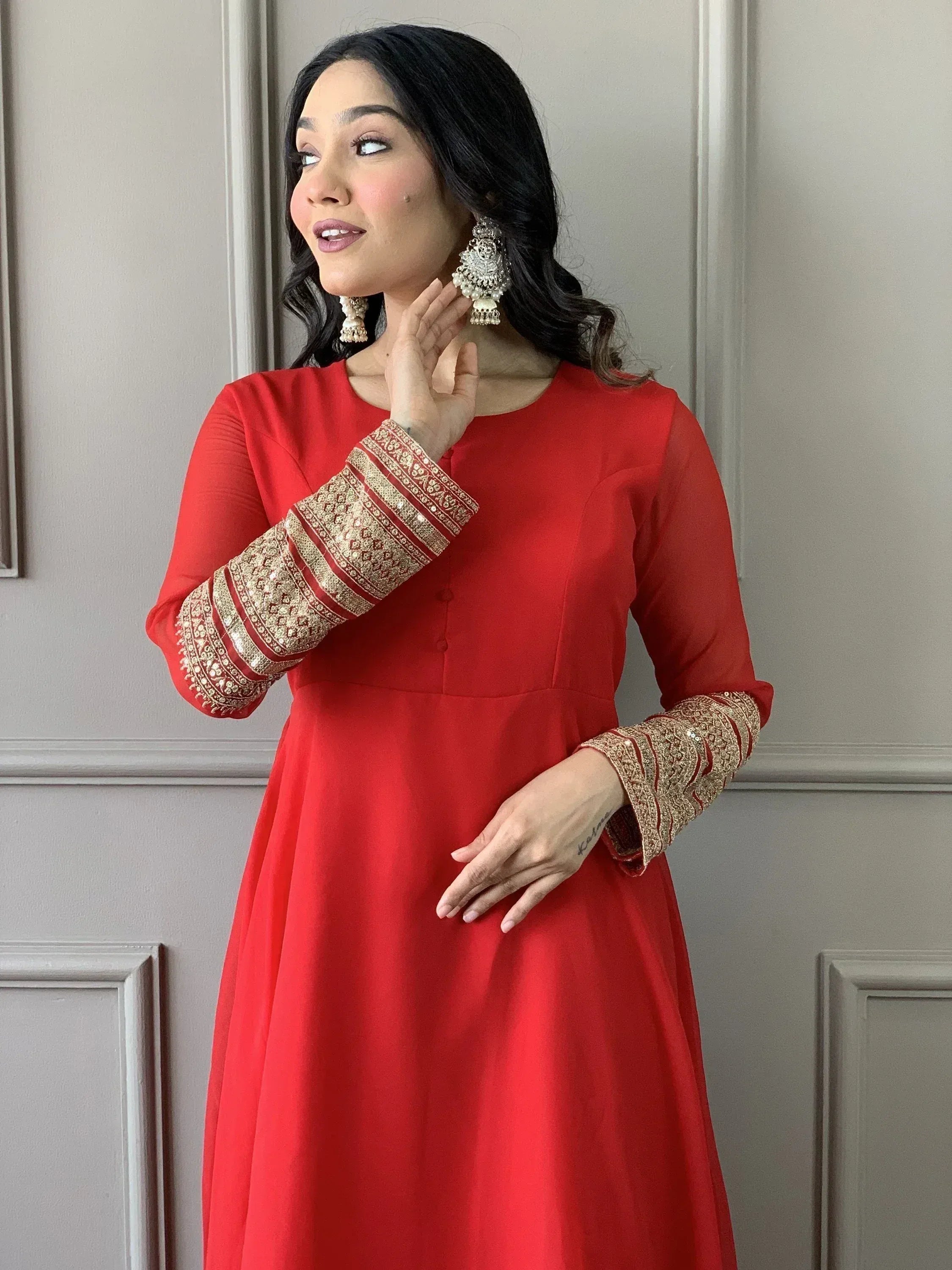 Red ethnic gown with gold embroidered sleeves and traditional jhumka earrings