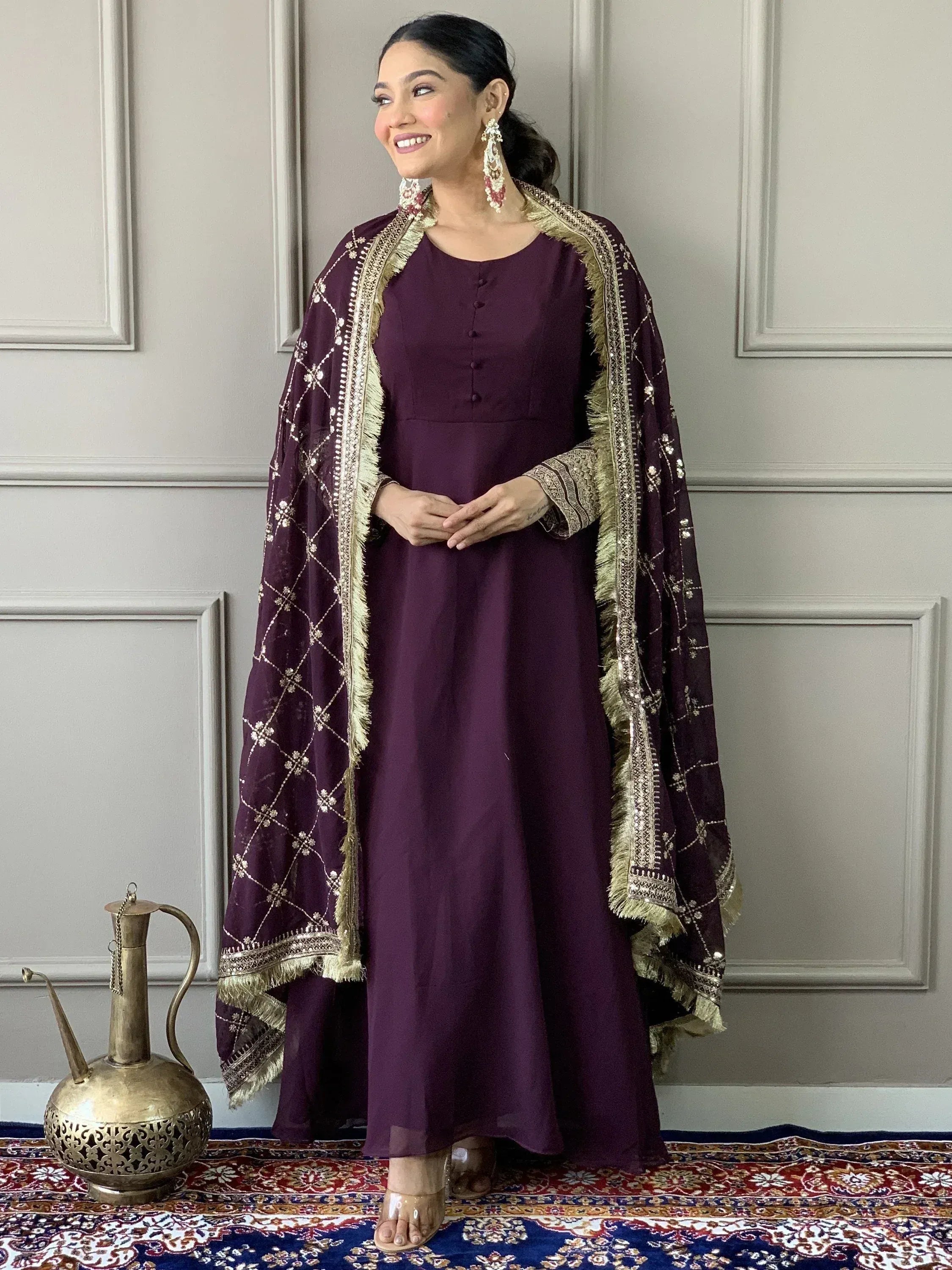 Elegant purple ethnic gown with gold embroidery and matching dupatta, styled for festive occasions.