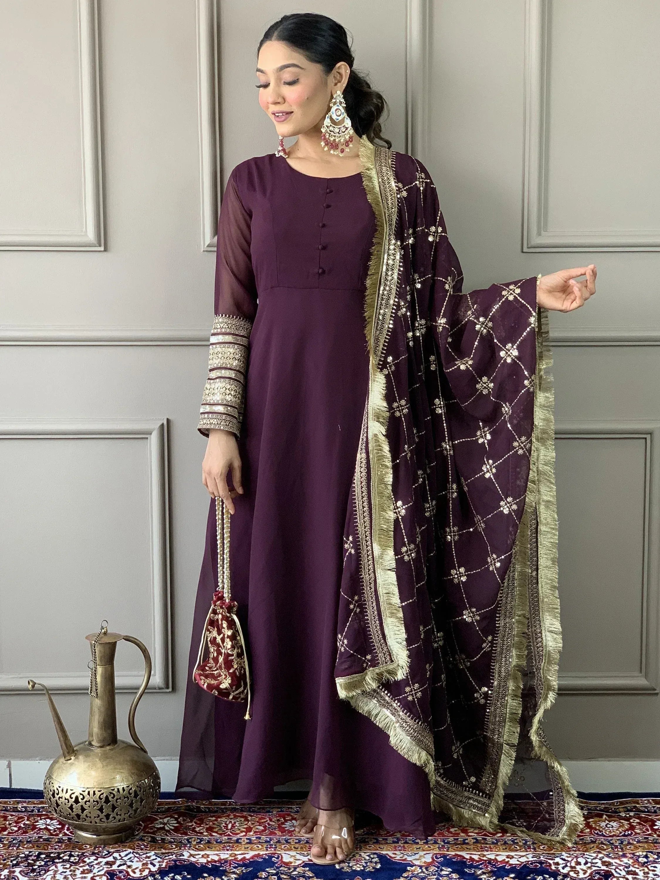 Elegant purple ethnic gown with gold embroidery and matching dupatta, styled with traditional jewelry.