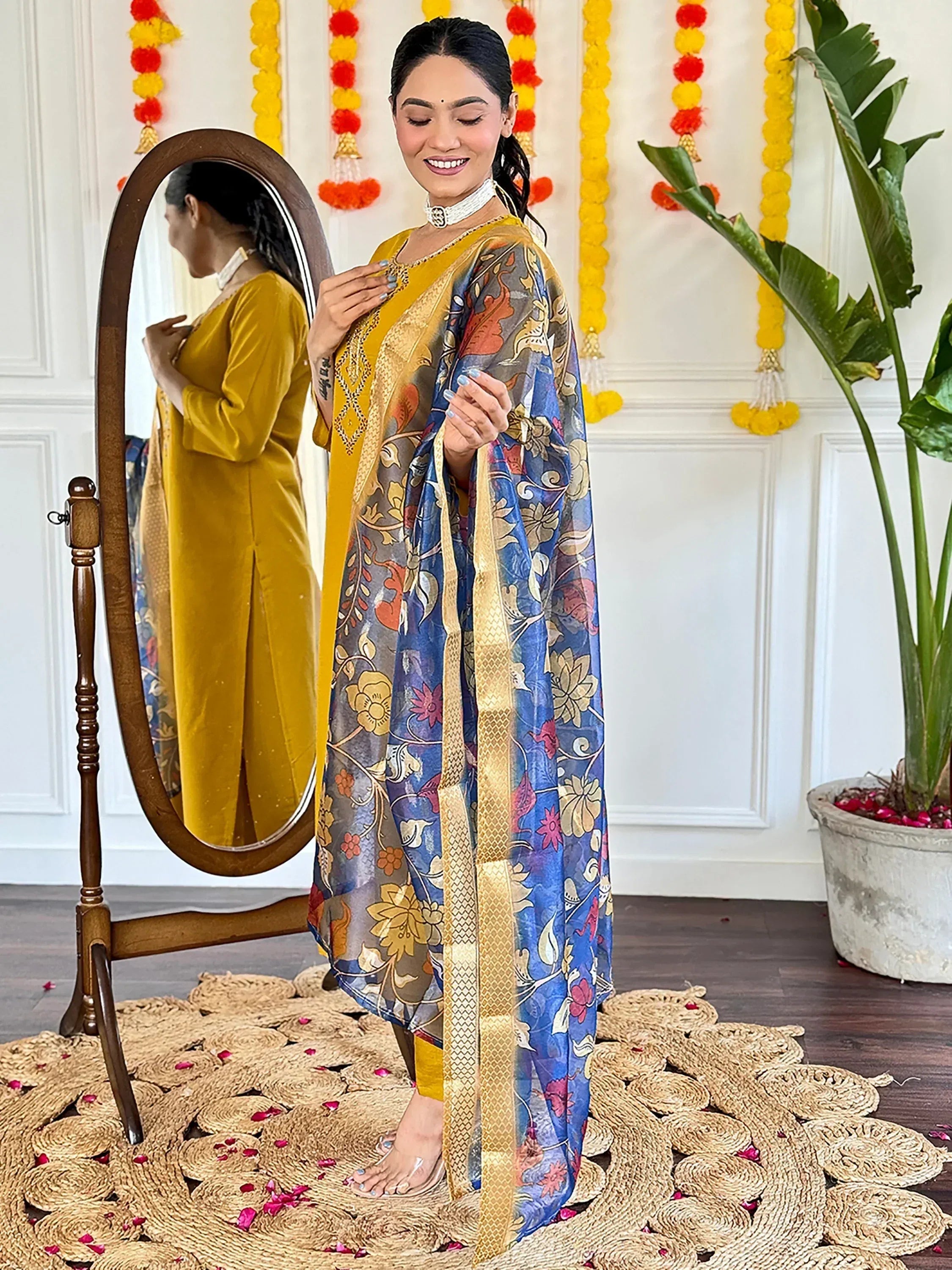 Woman in mustard yellow velvet kurta with floral blue dupatta, festive Indian ethnic wear
