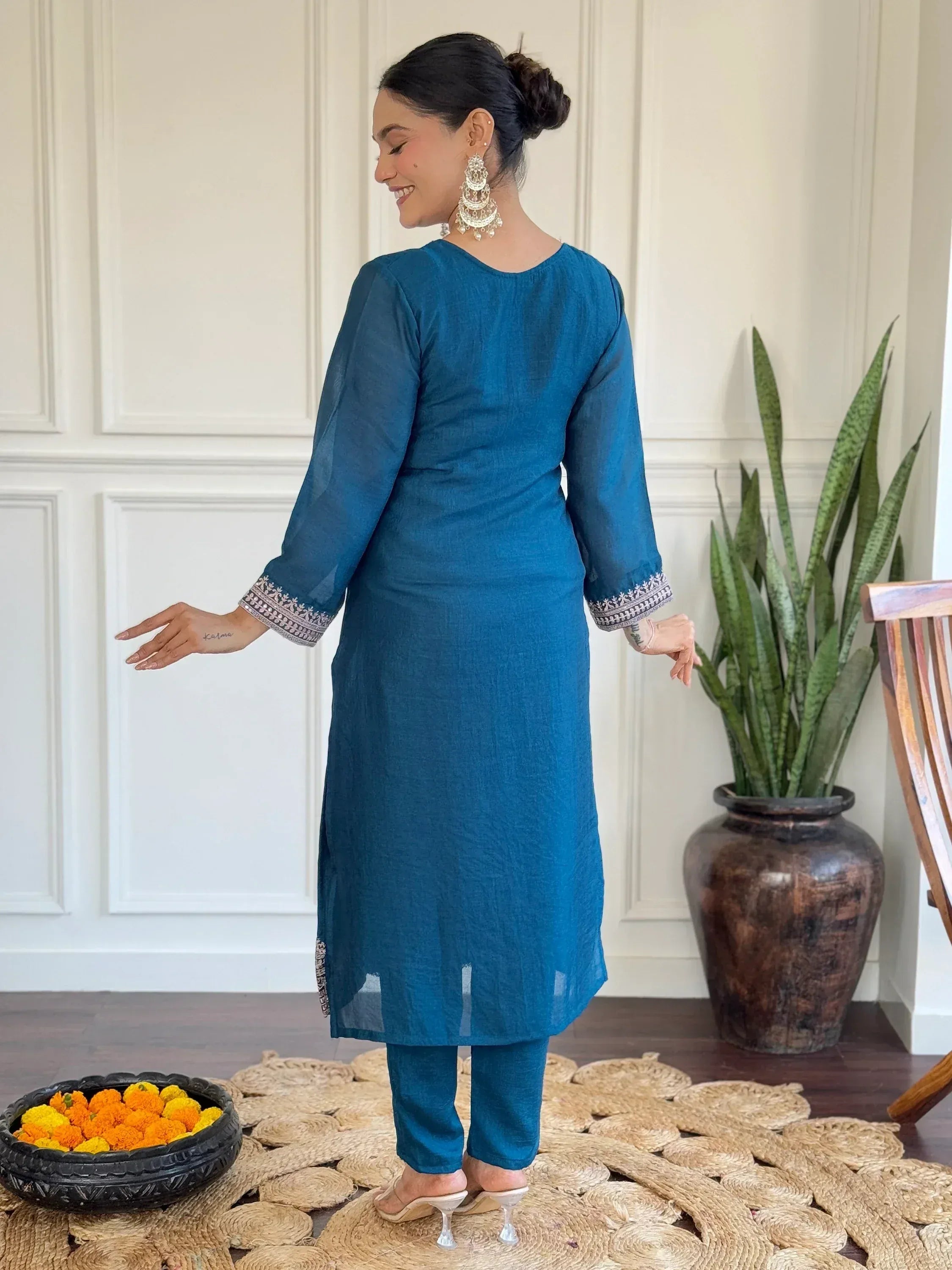 Teal blue ethnic kurta with embroidered sleeves and matching pants, styled with jhumka earrings for festive occasions.