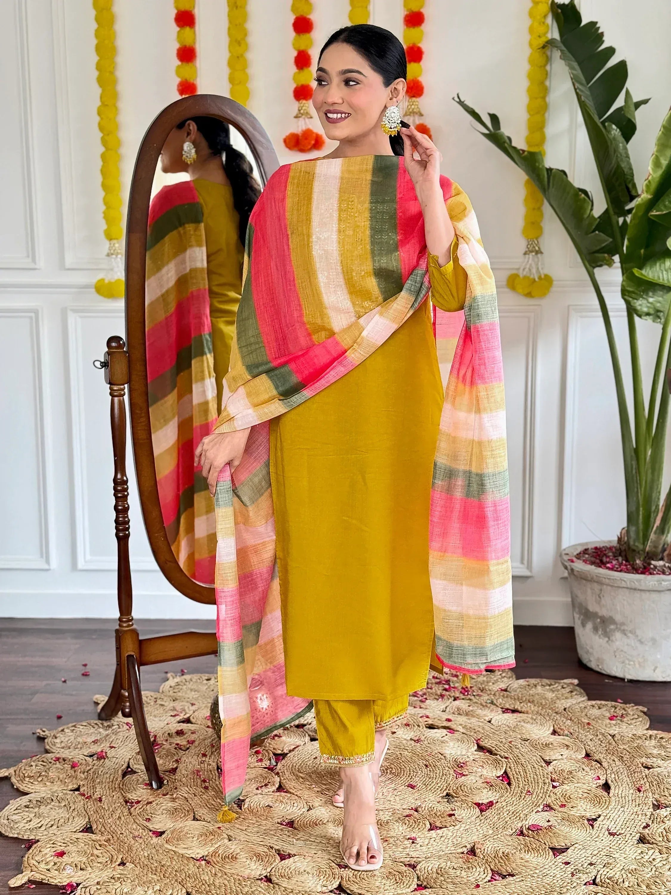 Woman in mustard yellow salwar kameez with colorful striped dupatta, festive Indian ethnic wear