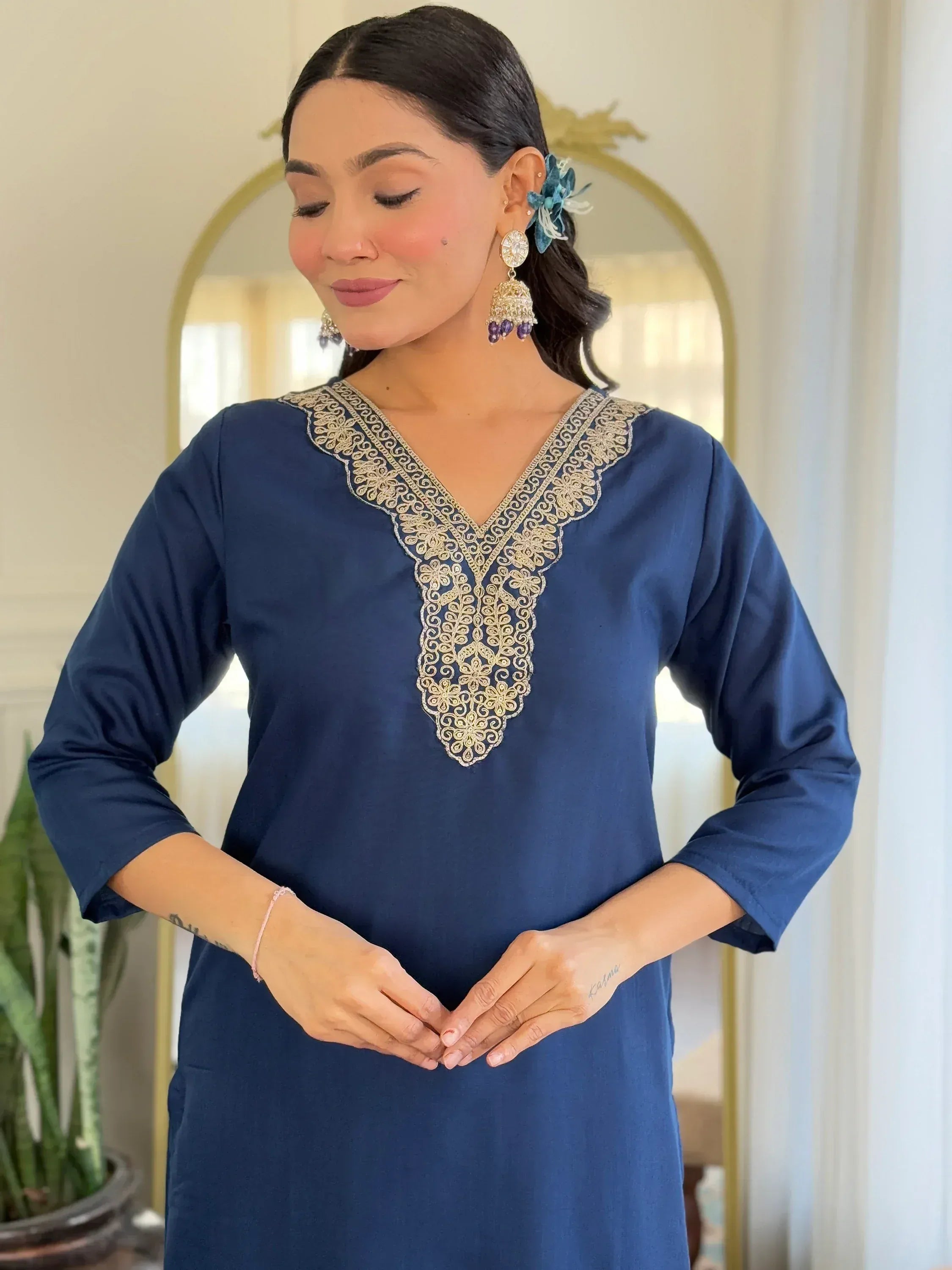 Navy blue ethnic kurti with gold embroidery, paired with statement earrings and floral hair accessory.