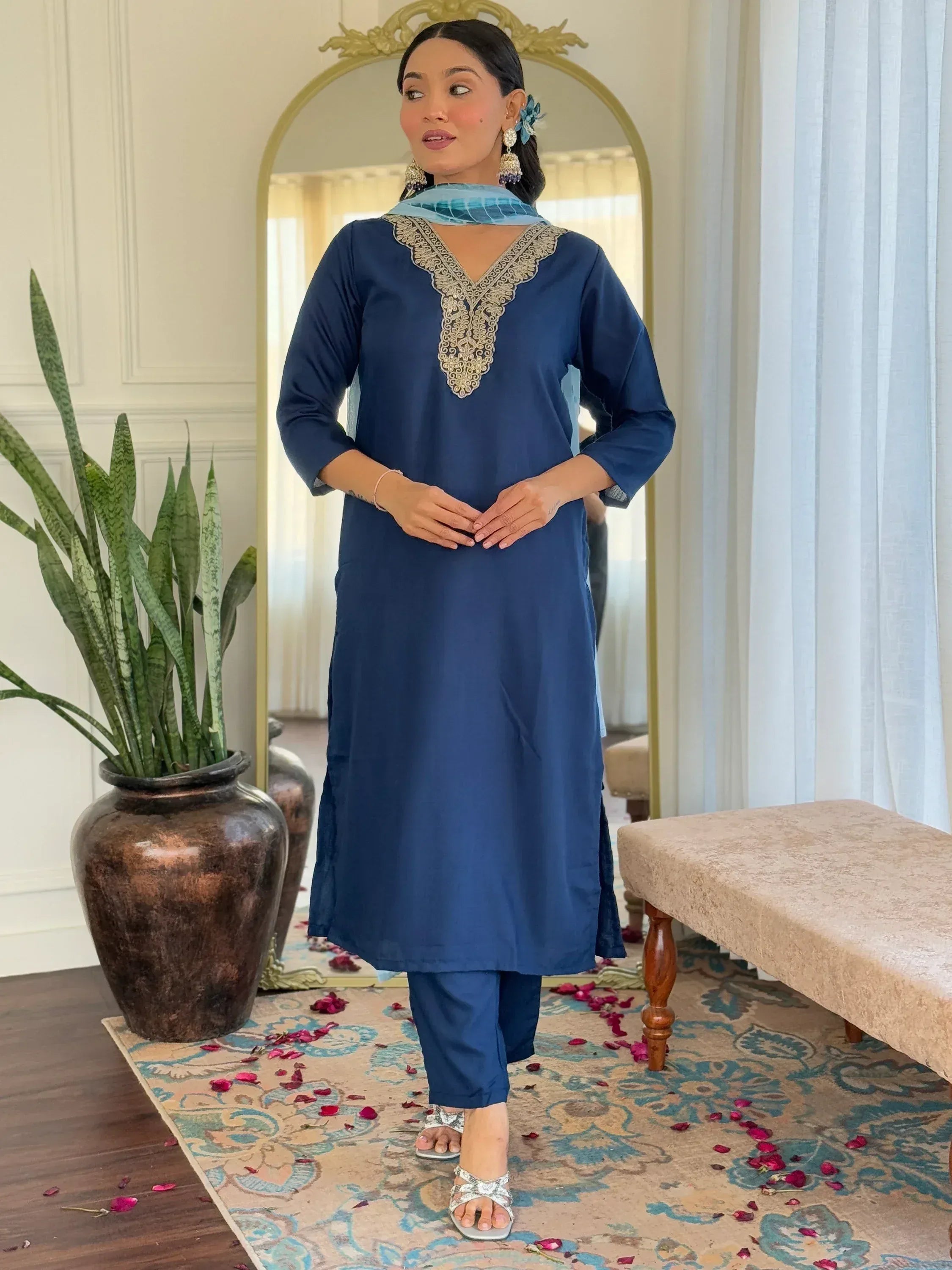 Blue embroidered kurta with matching pants and dupatta, styled with silver sandals and floral accessories.