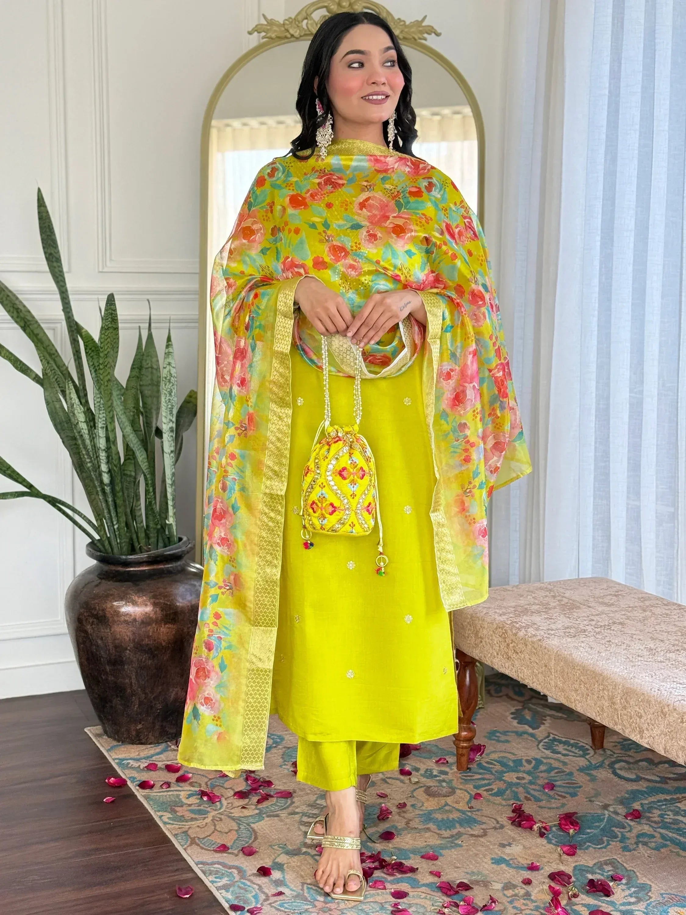 Vibrant yellow salwar kameez with floral dupatta and matching potli bag, perfect for festive occasions.