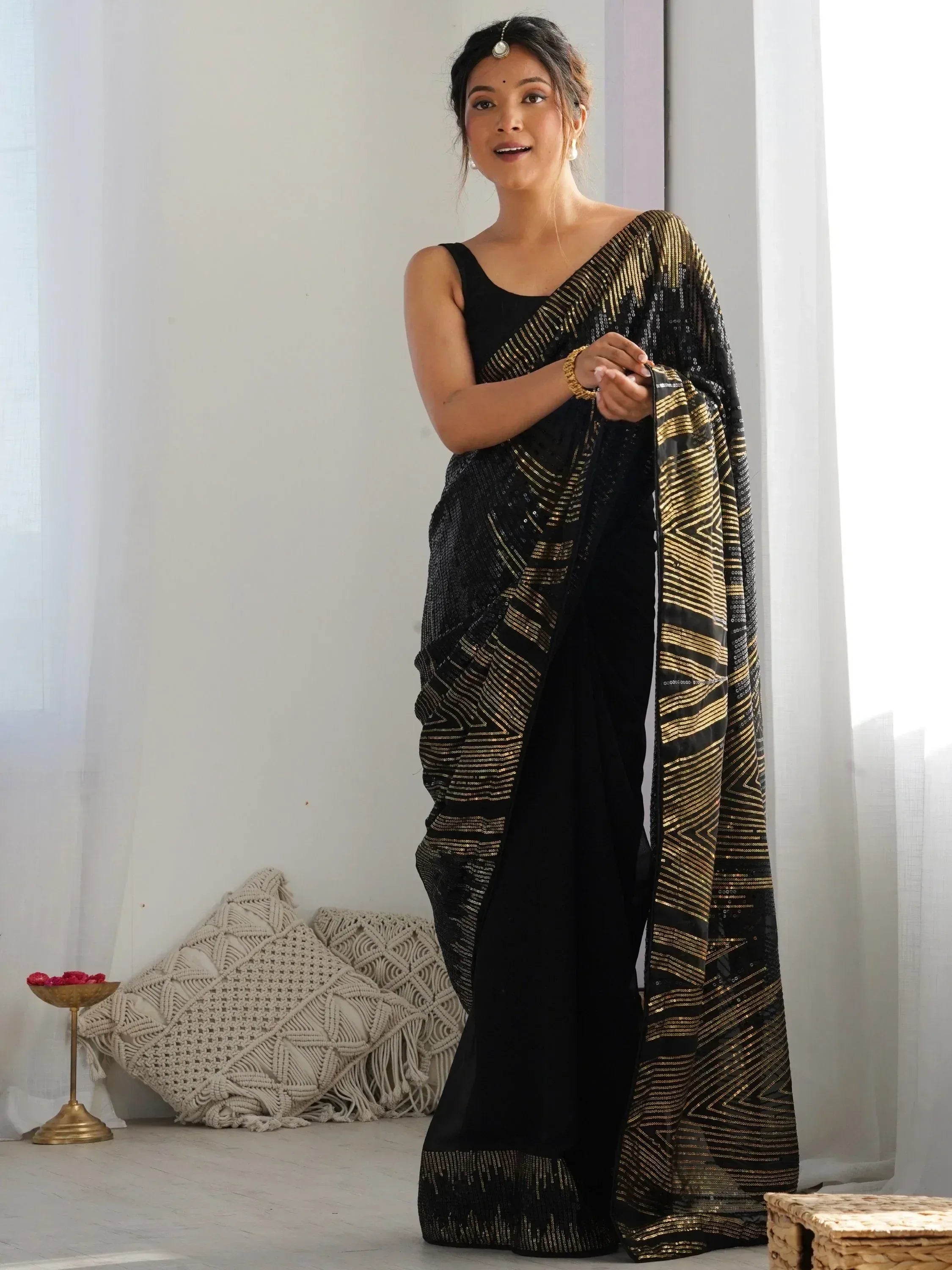 Black and gold sequin saree with geometric patterns, styled with a black sleeveless top for ethnic wear.