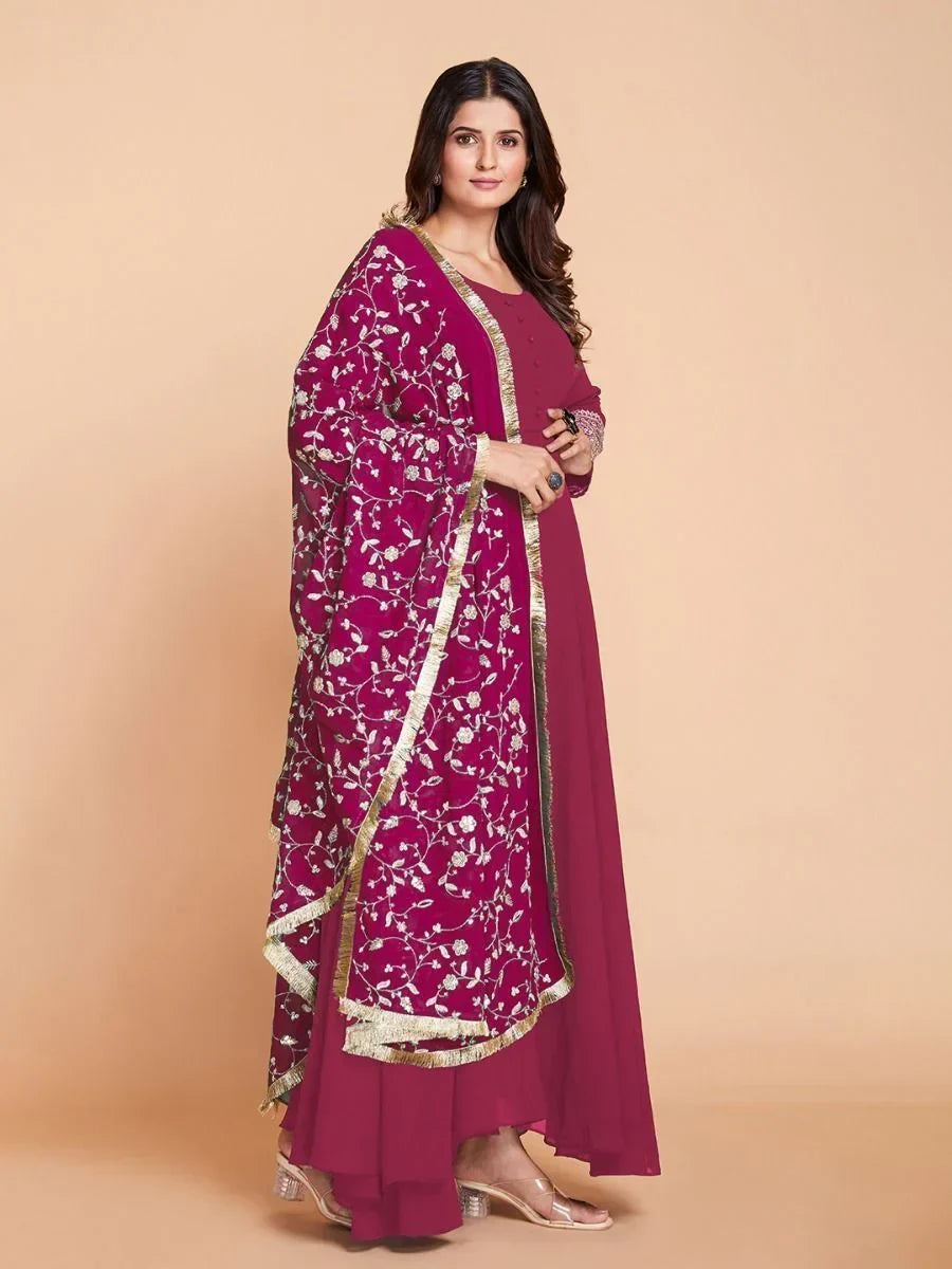 Woman wearing magenta ethnic gown with embroidered dupatta and gold border