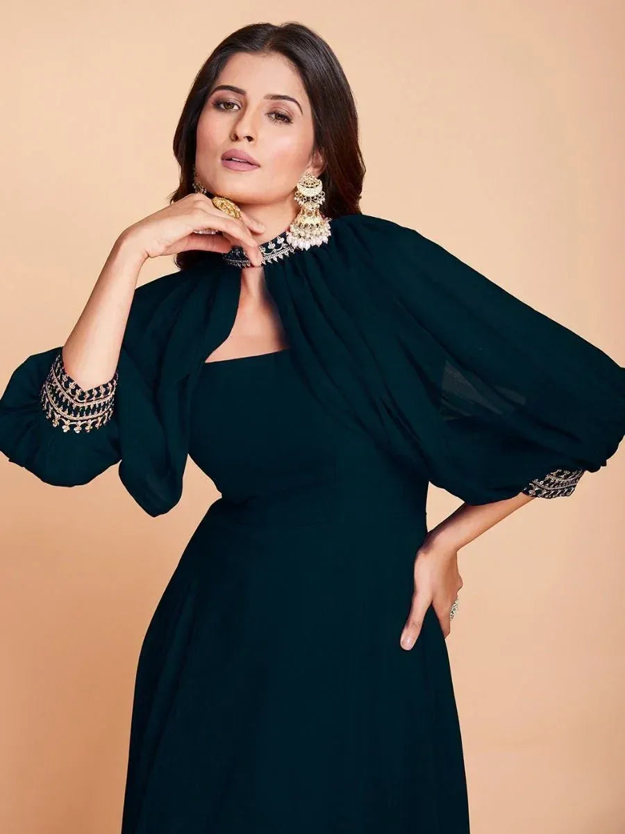 Elegant dark green ethnic gown with embroidered sleeves and cape, paired with statement jewelry