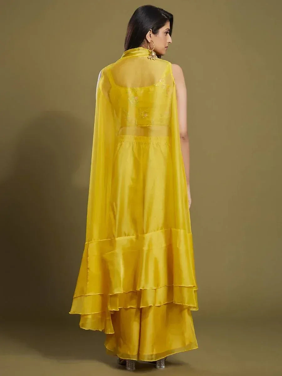 Woman in sleeveless yellow ethnic gown with sheer dupatta and layered skirt, back view