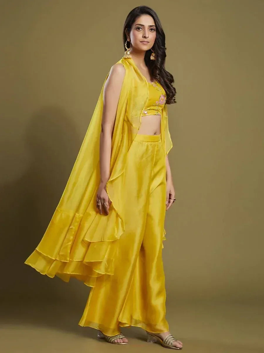 Woman wearing a yellow designer crop top and palazzo ethnic set with ruffle cape.