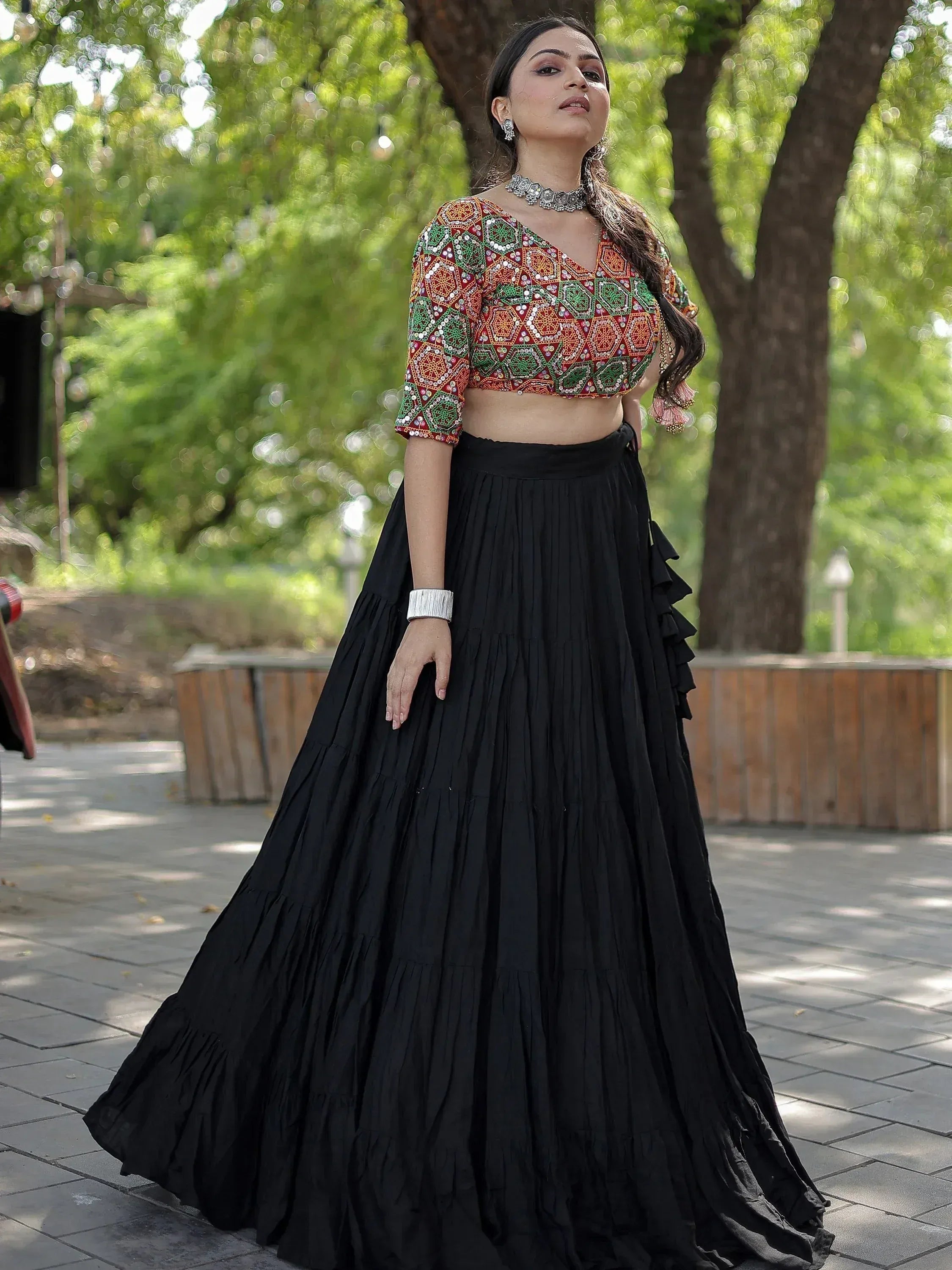 Woman in embroidered crop top and black pleated lehenga skirt, ethnic Indian wear