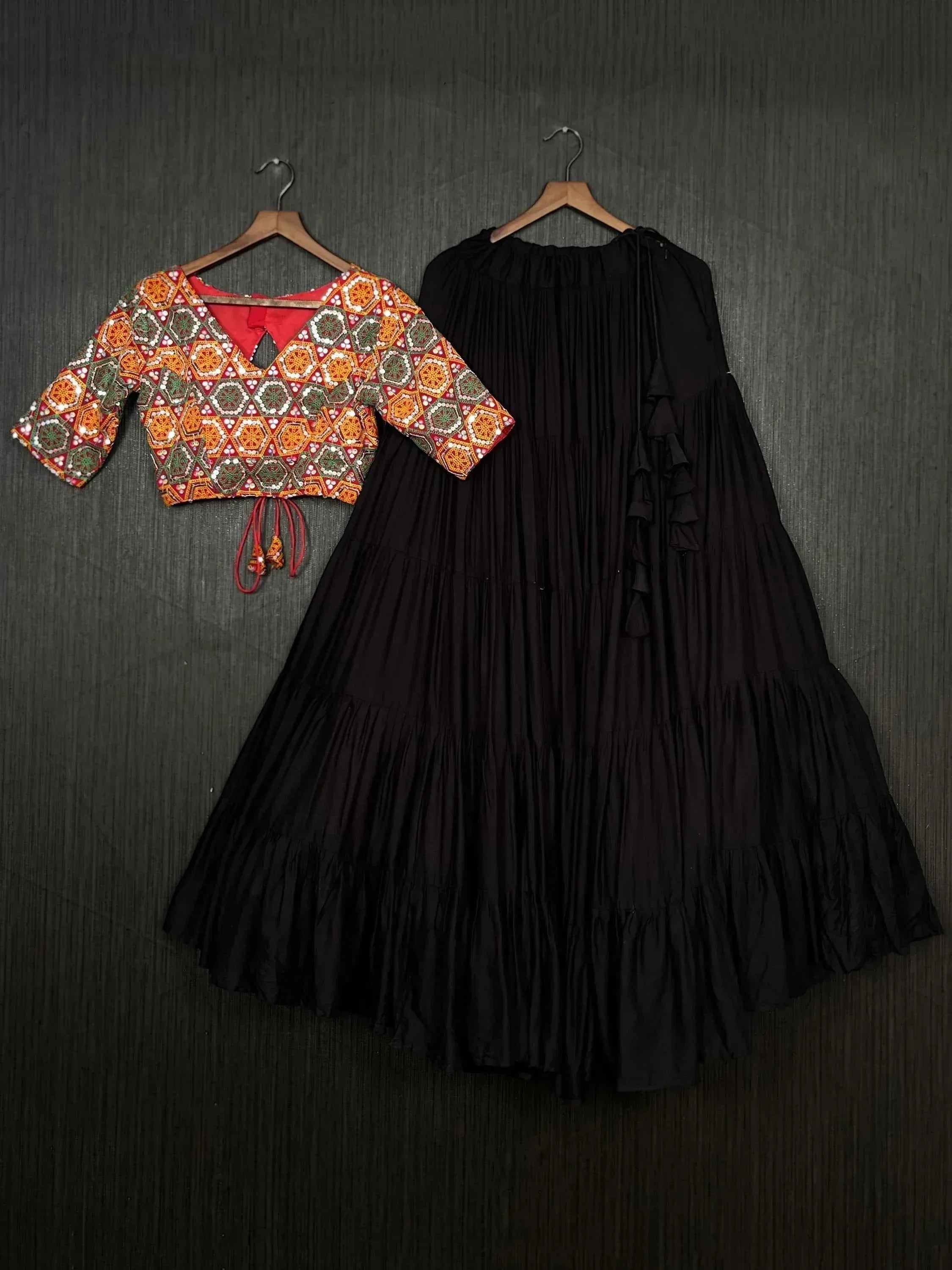 Ethnic Indian outfit with embroidered red crop top and black tiered skirt, perfect for festive occasions.