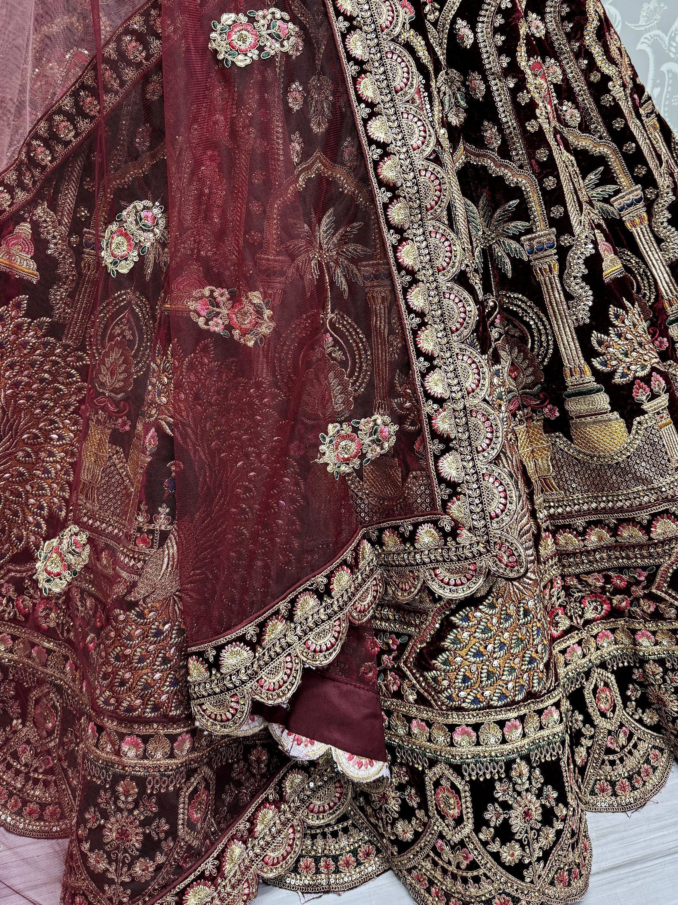 Luxury maroon velvet lehenga choli with intricate gold embroidery and floral motifs, perfect for weddings.