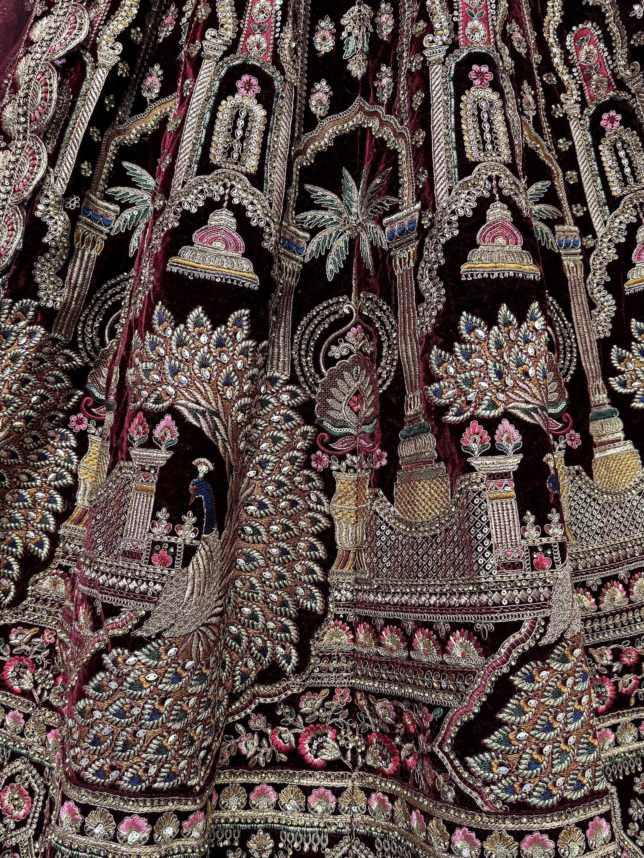 Luxury maroon velvet lehenga with intricate peacock and temple embroidery, perfect for Indian weddings.