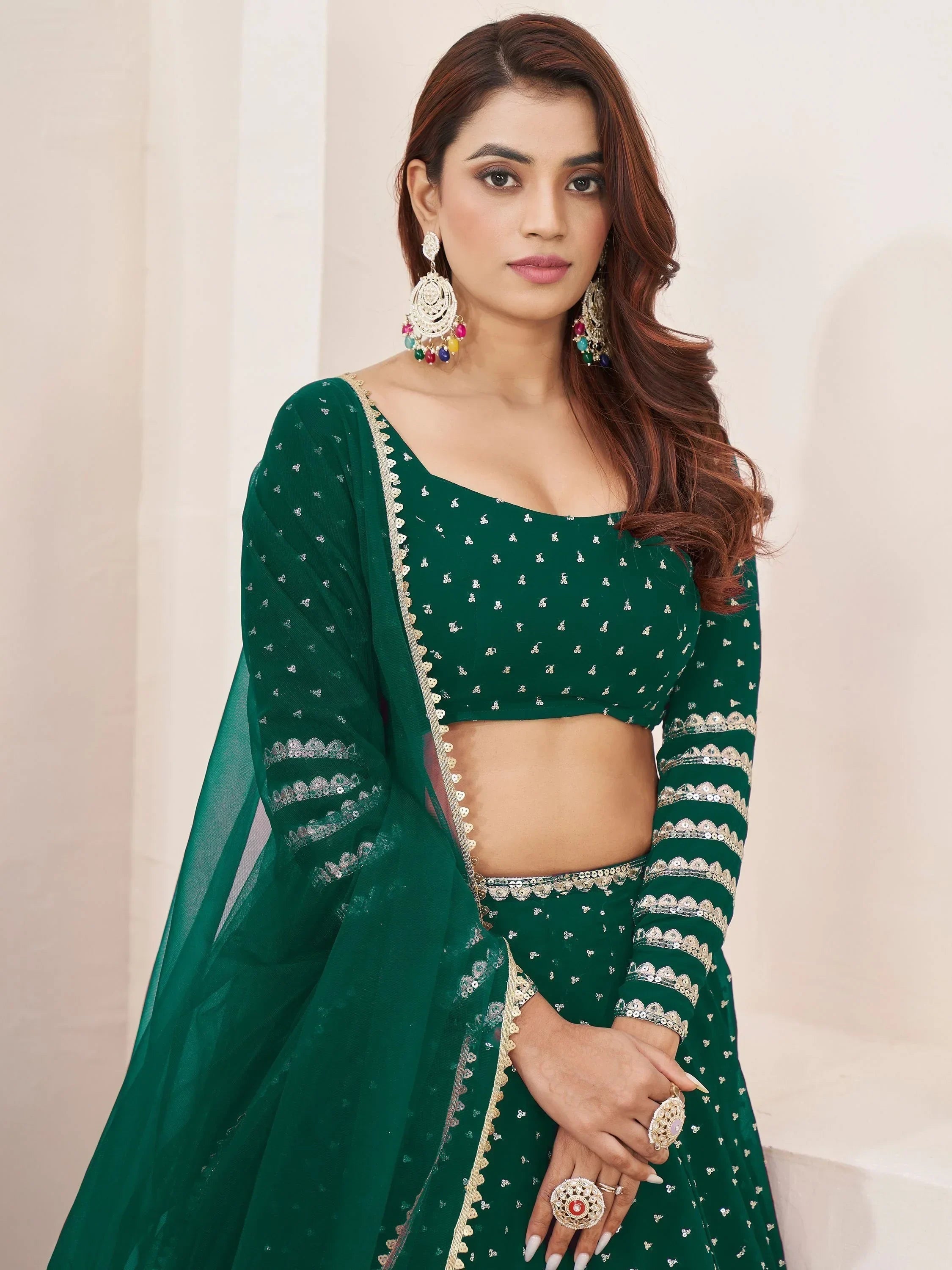 Emerald green embroidered lehenga choli with sequin work and matching dupatta, styled with statement earrings