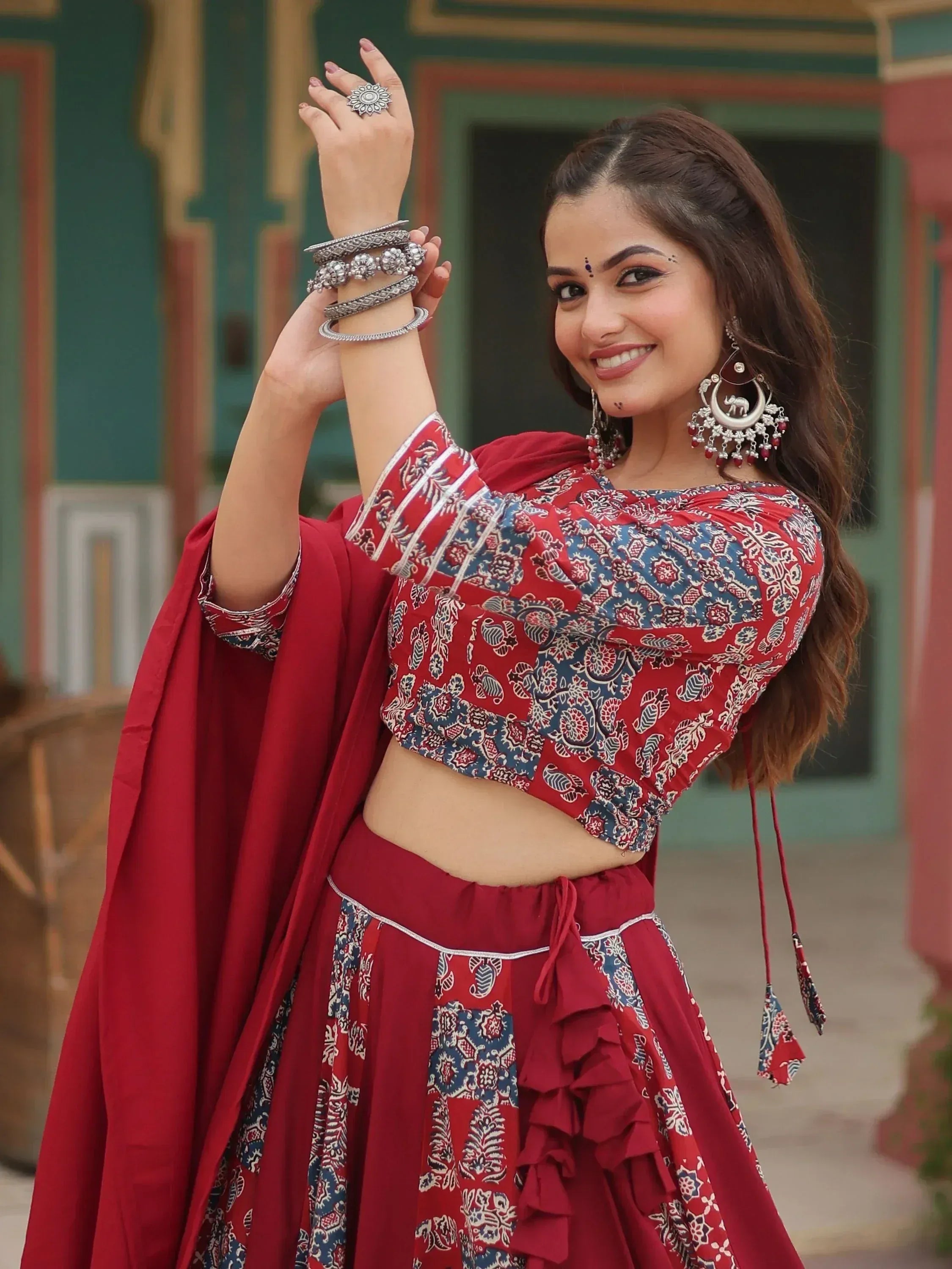 Woman in red printed lehenga choli with ruffles, silver jewelry, and traditional Indian ethnic wear