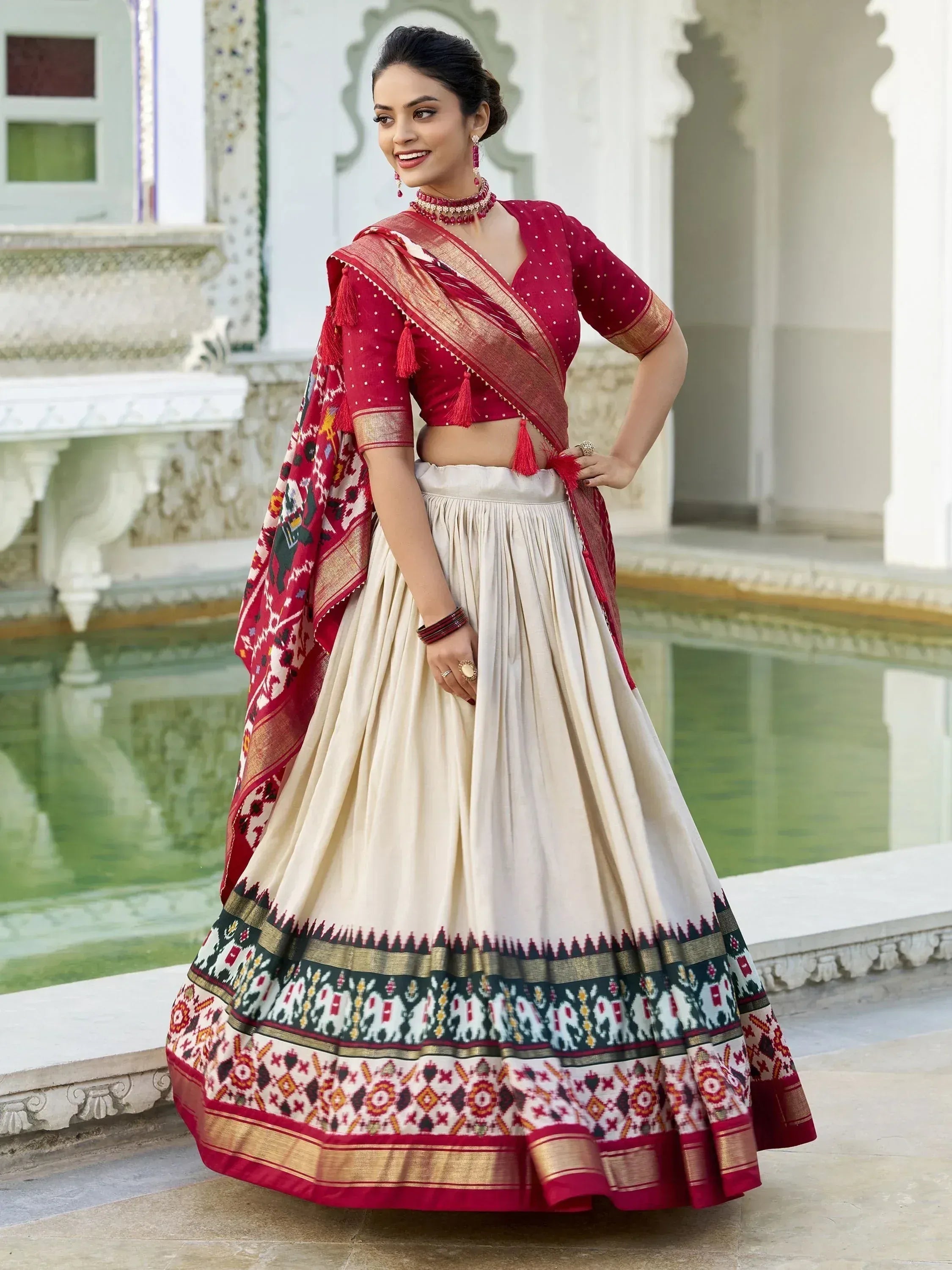 Woman in red and cream ethnic lehenga choli with elephant print, perfect for Indian weddings or festivals.