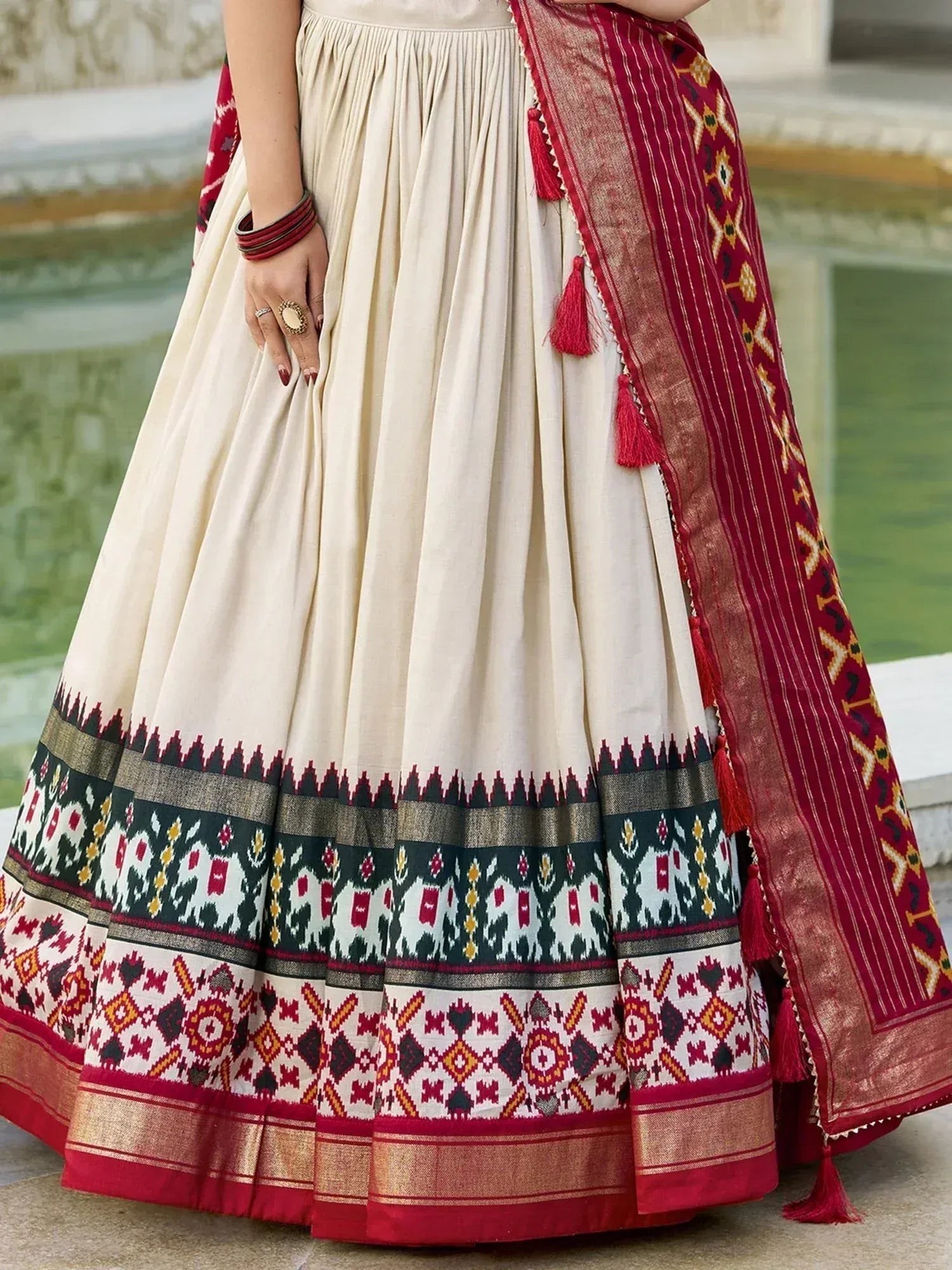 Cream ethnic lehenga with red and gold geometric border, paired with matching dupatta, ideal for Indian weddings and festivals.