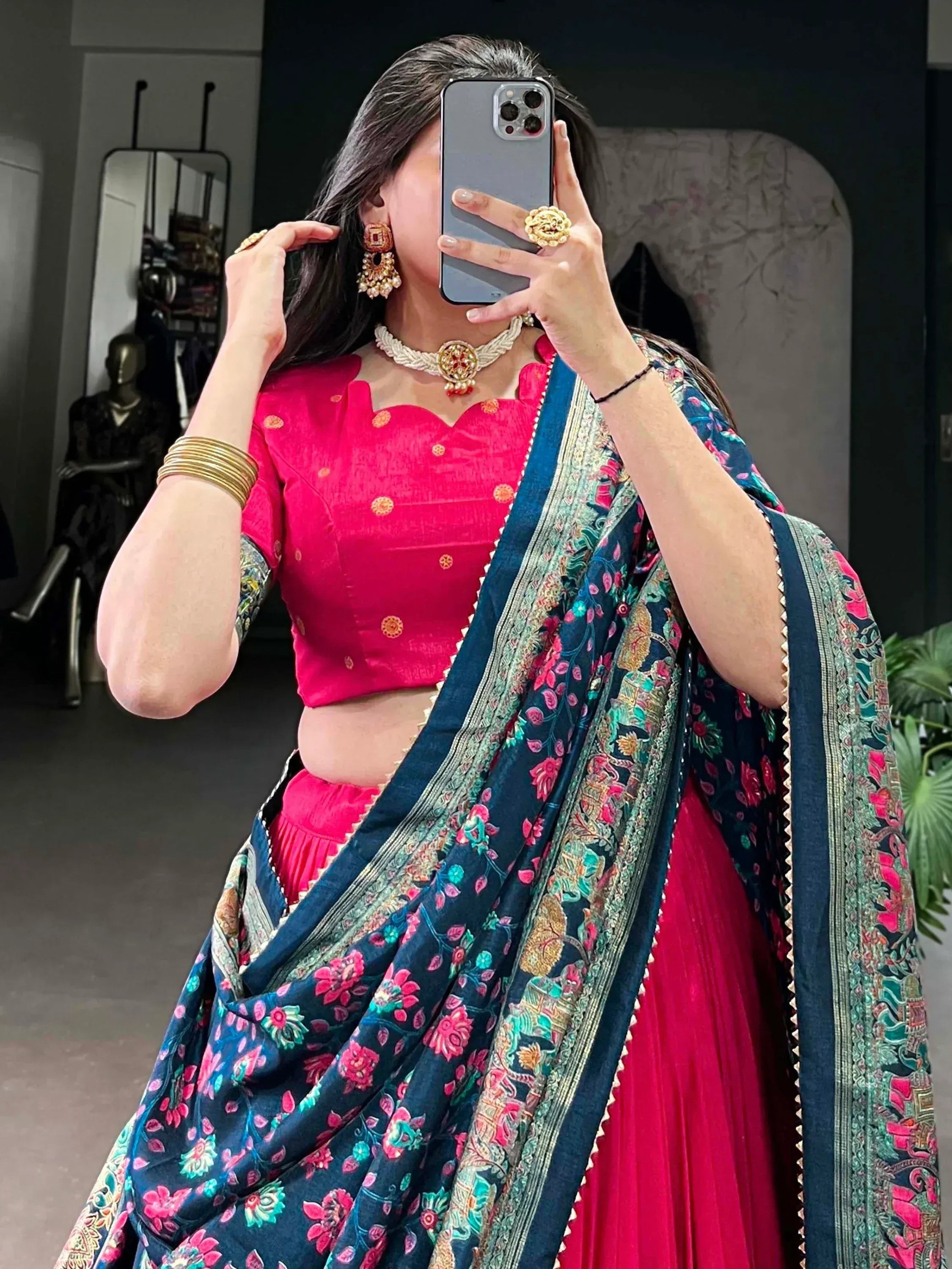 Woman in vibrant pink lehenga choli with floral navy dupatta, traditional Indian ethnic wear