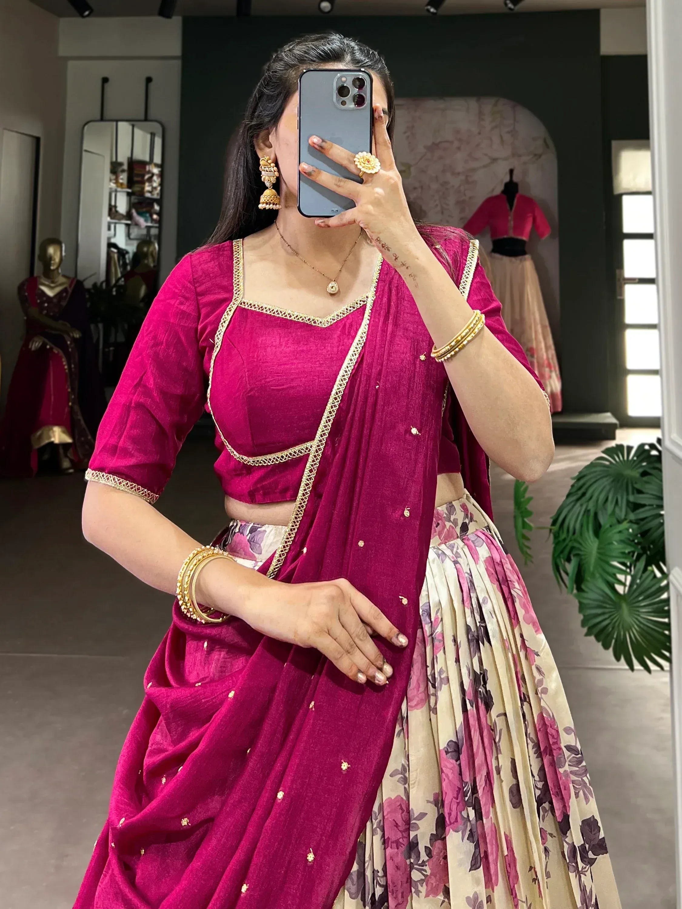 Woman in magenta lehenga choli with gold trim, floral skirt, and traditional jewelry