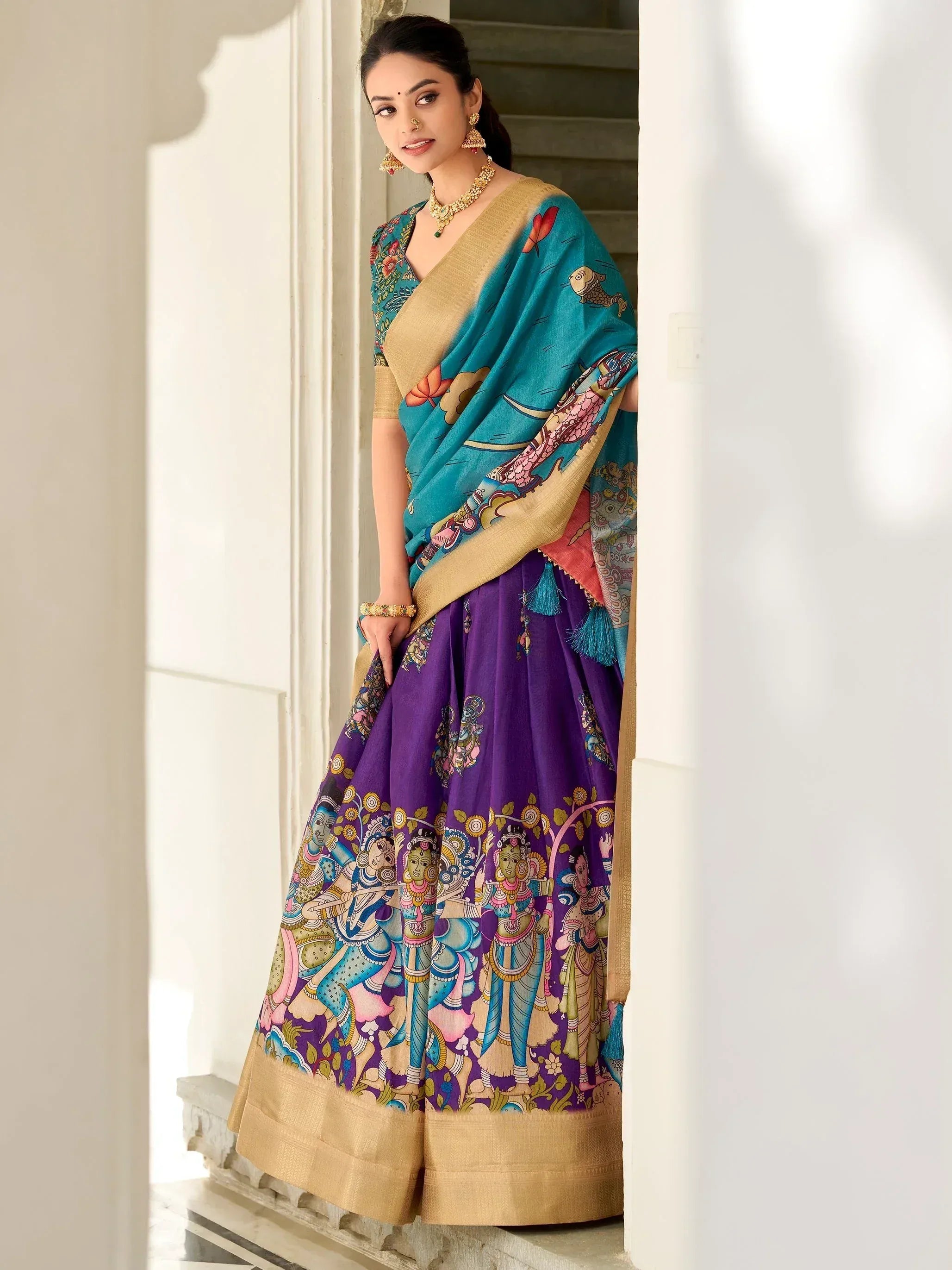 Woman in vibrant purple and teal printed lehenga choli with gold border, traditional Indian ethnic wear
