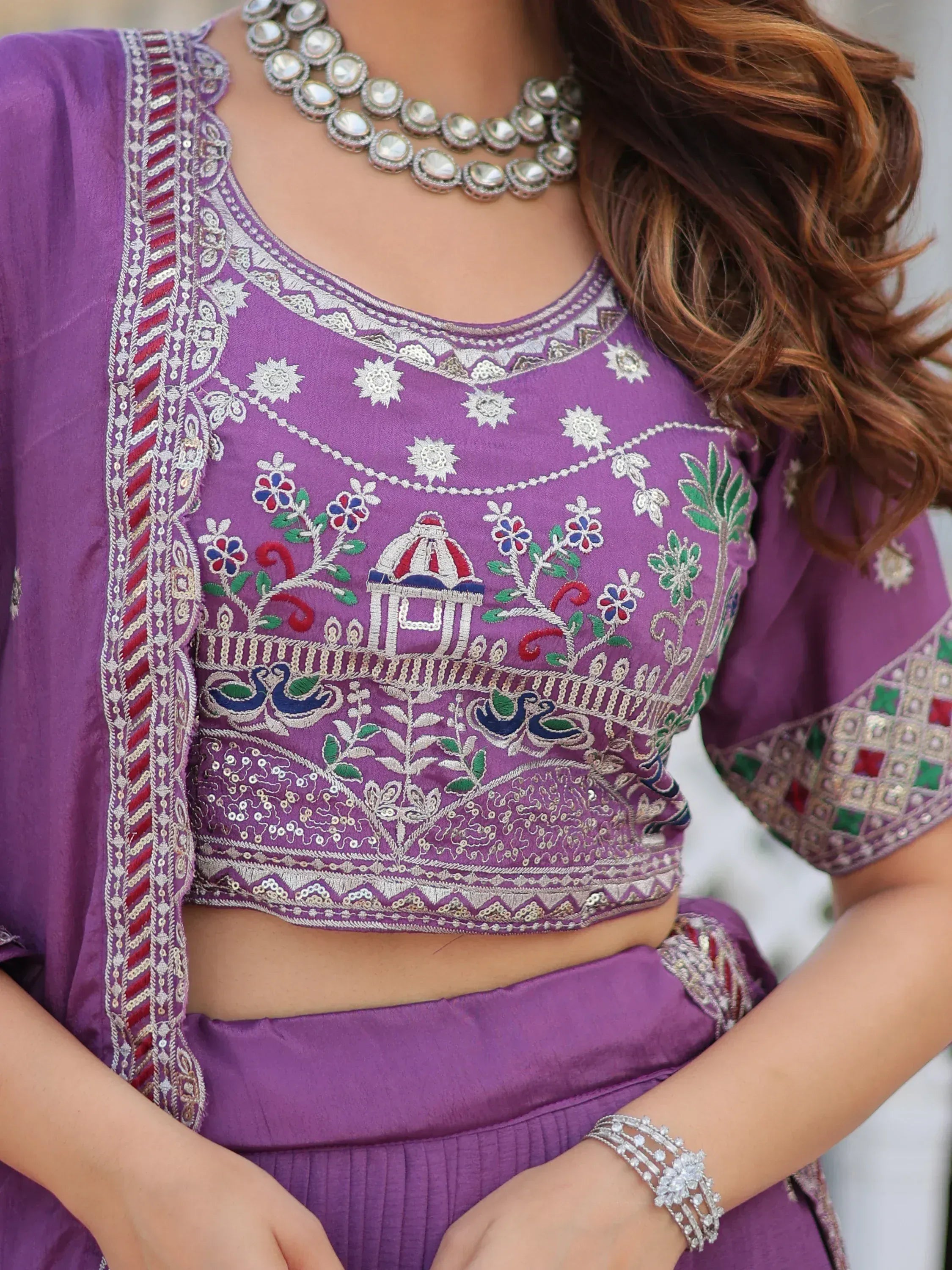 Purple embroidered lehenga choli with floral and peacock motifs, paired with statement jewelry