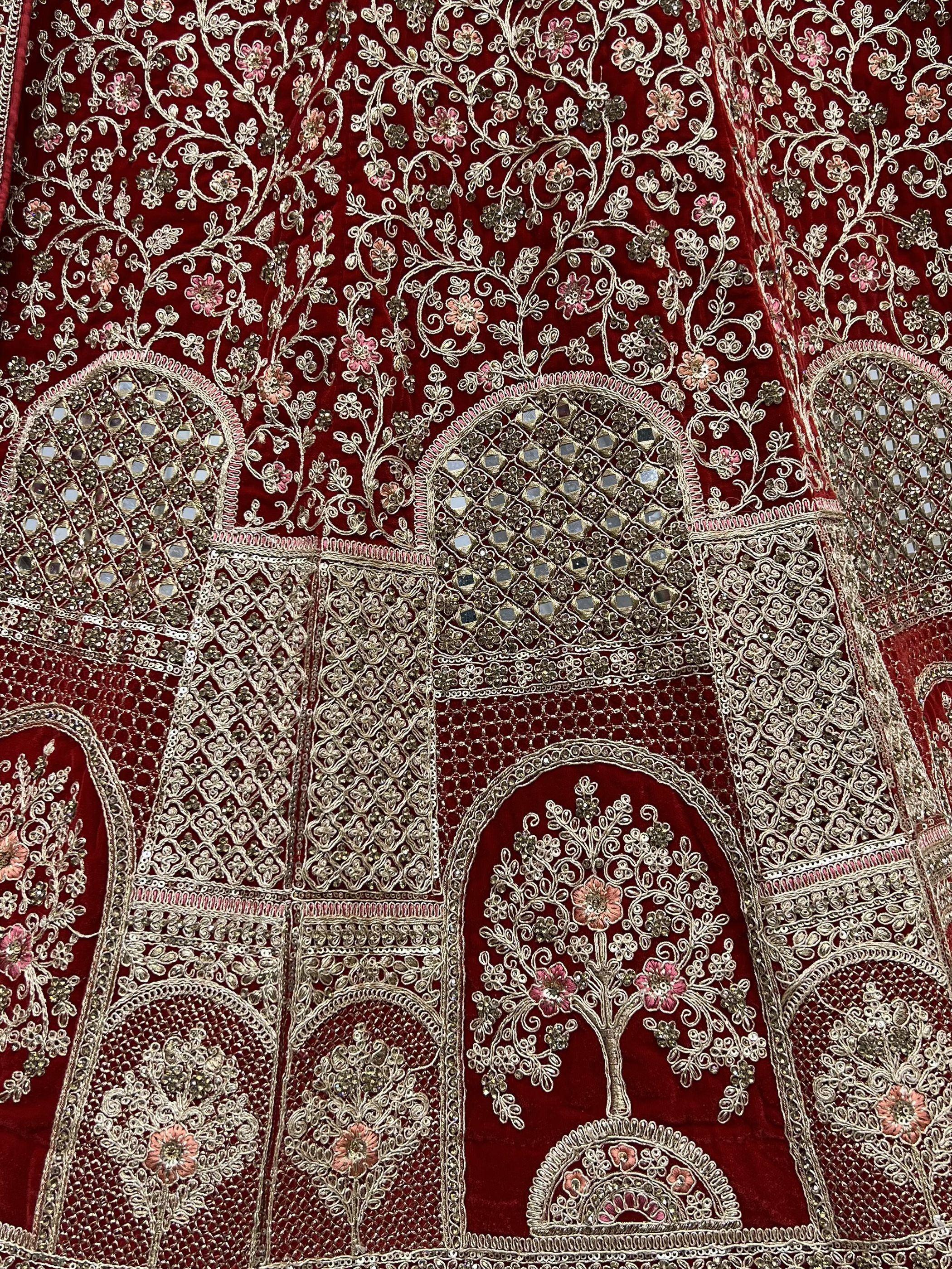 Luxury red velvet lehenga with intricate gold embroidery, floral motifs, and mirror work detailing.