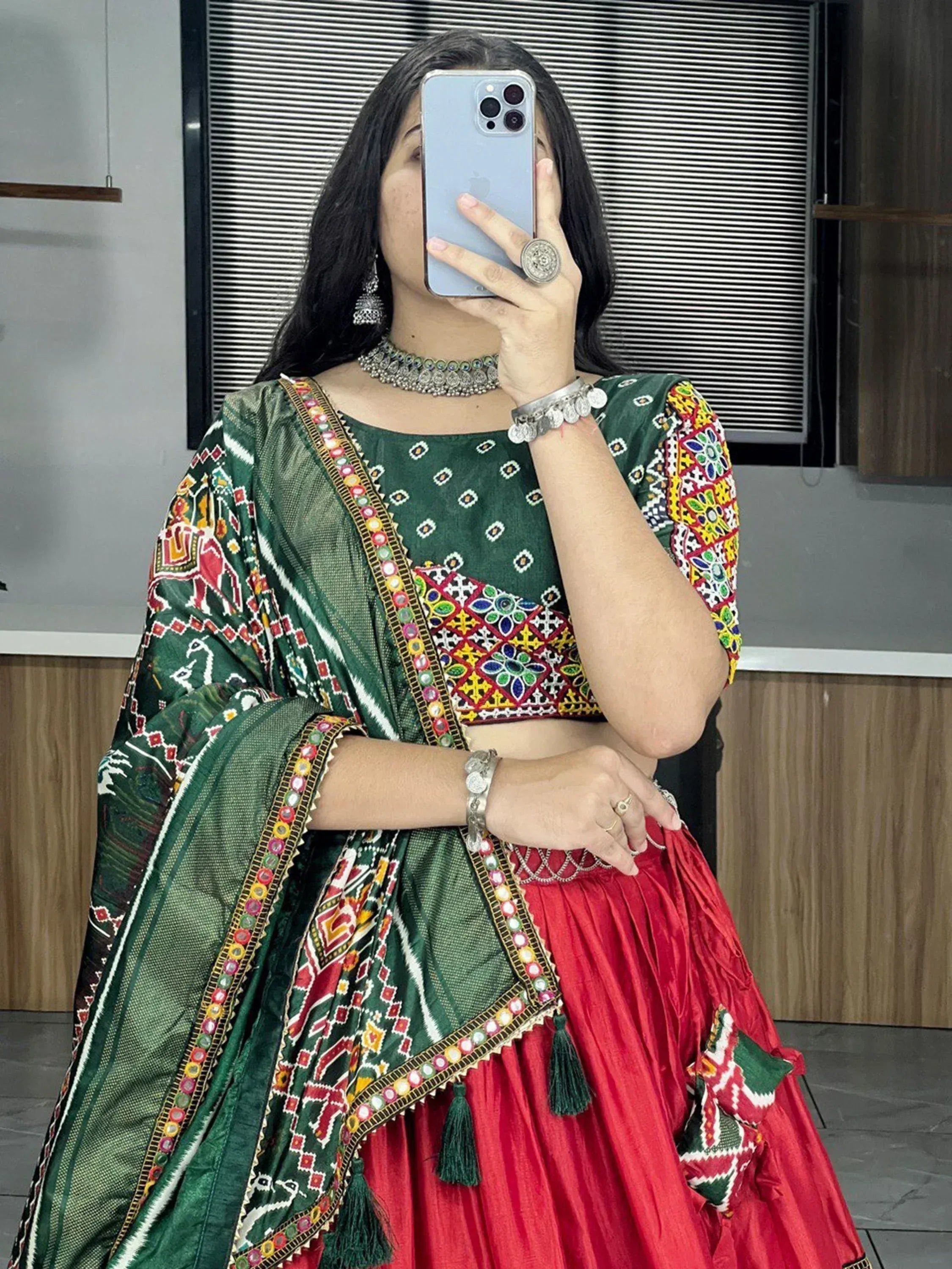Green and red ethnic lehenga choli with mirror work and embroidery, perfect for Indian festive occasions.