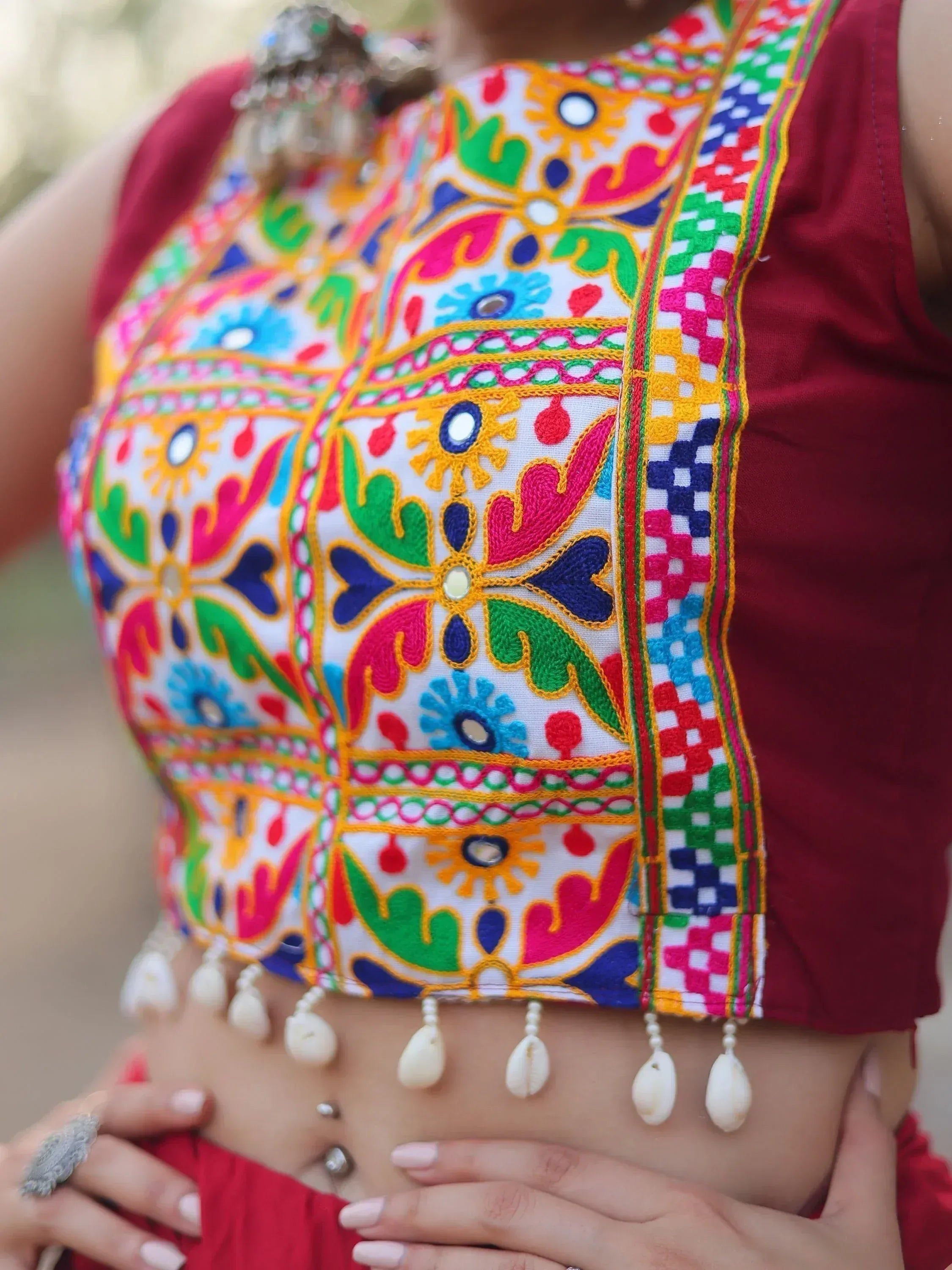 Vibrant Indian ethnic crop top with mirror work, colorful embroidery, and shell tassels for festive wear