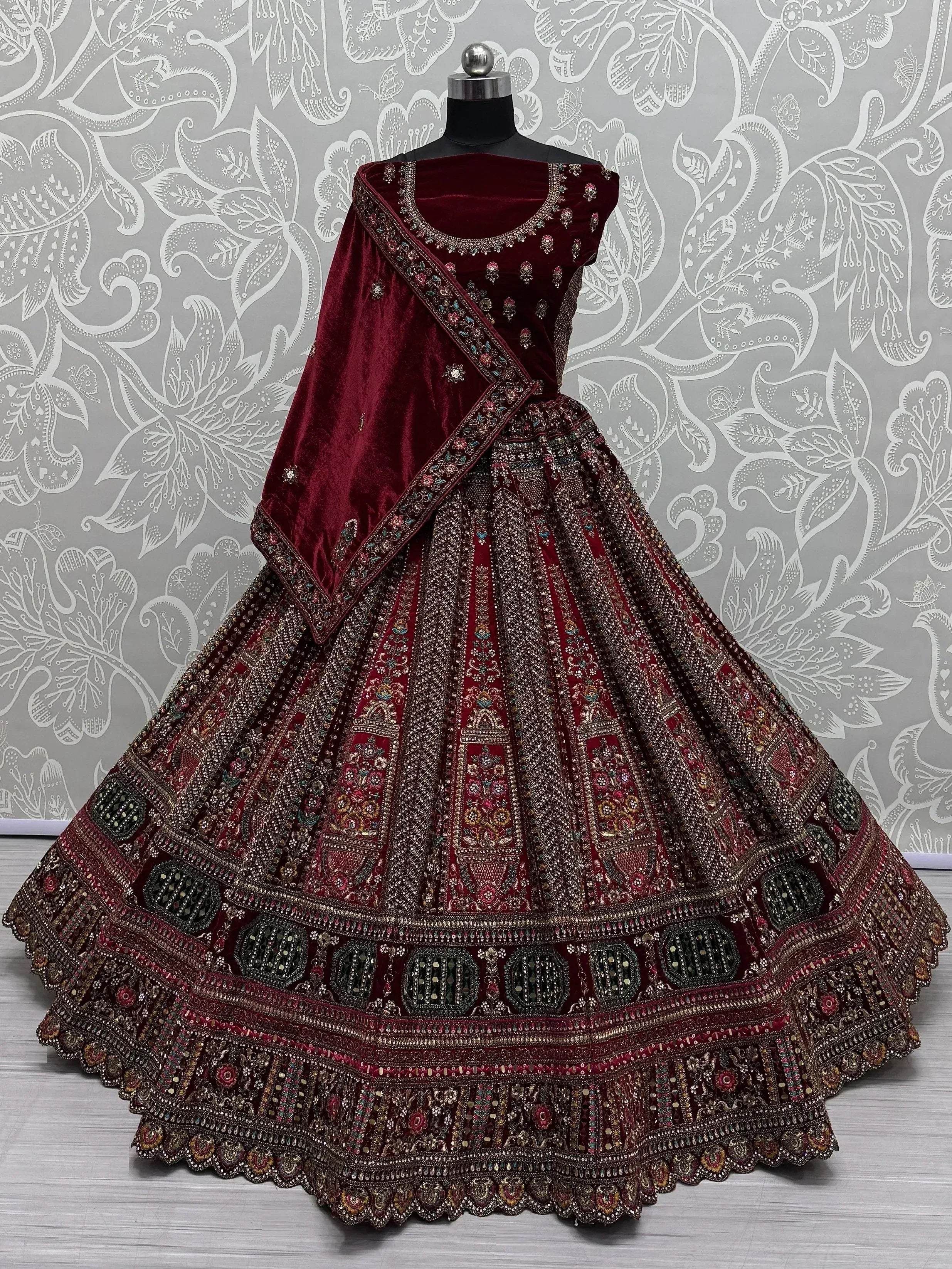 Maroon velvet designer lehenga choli with heavy embroidery and mirror work, perfect for Indian weddings