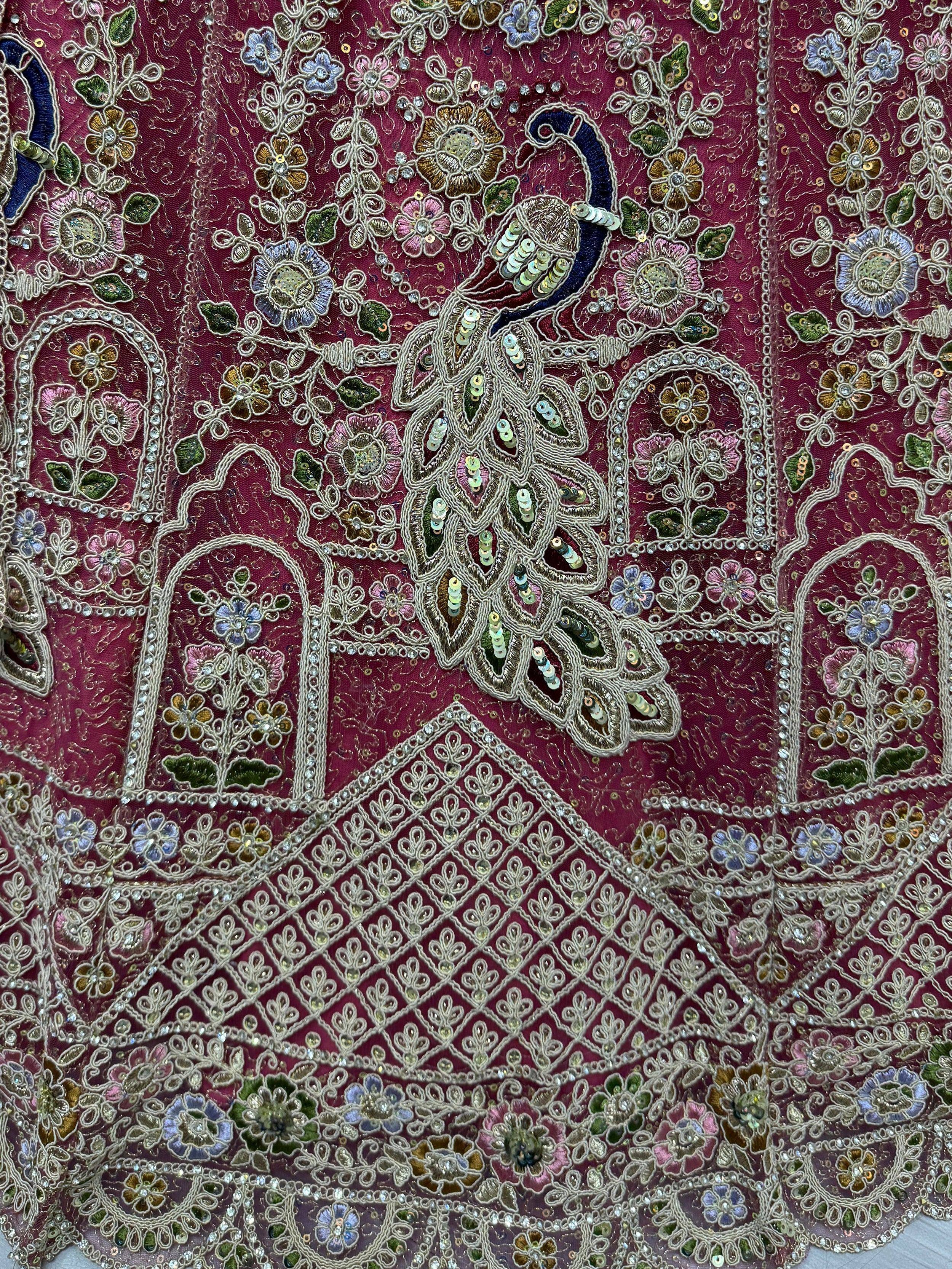 Luxury Indian ethnic wear with intricate floral embroidery, sequins, and peacock motifs on maroon fabric.