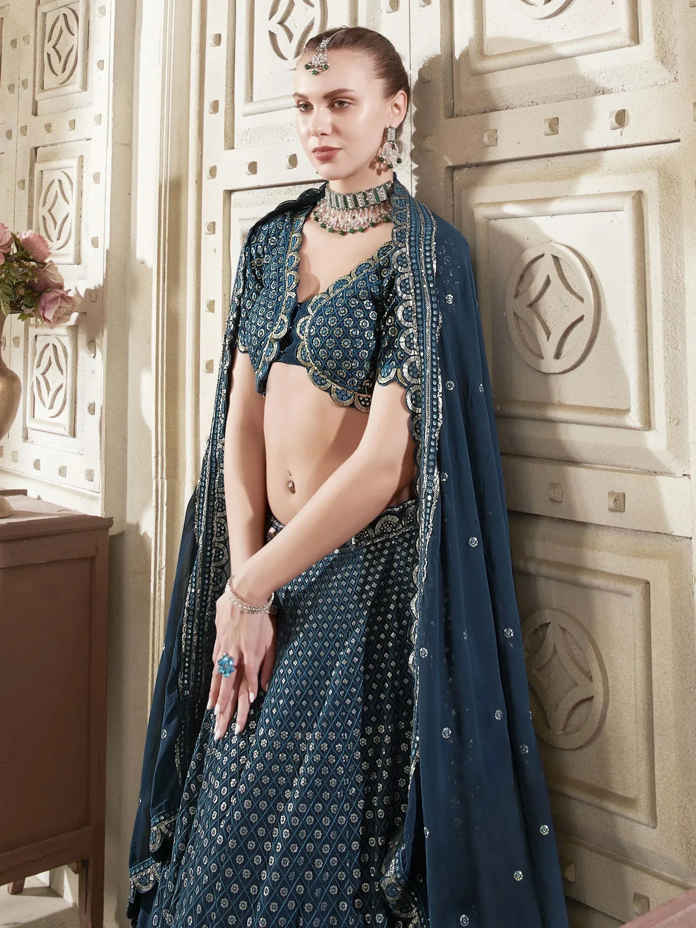 Elegant teal lehenga choli with intricate gold embroidery and matching dupatta, styled with traditional Indian jewelry.
