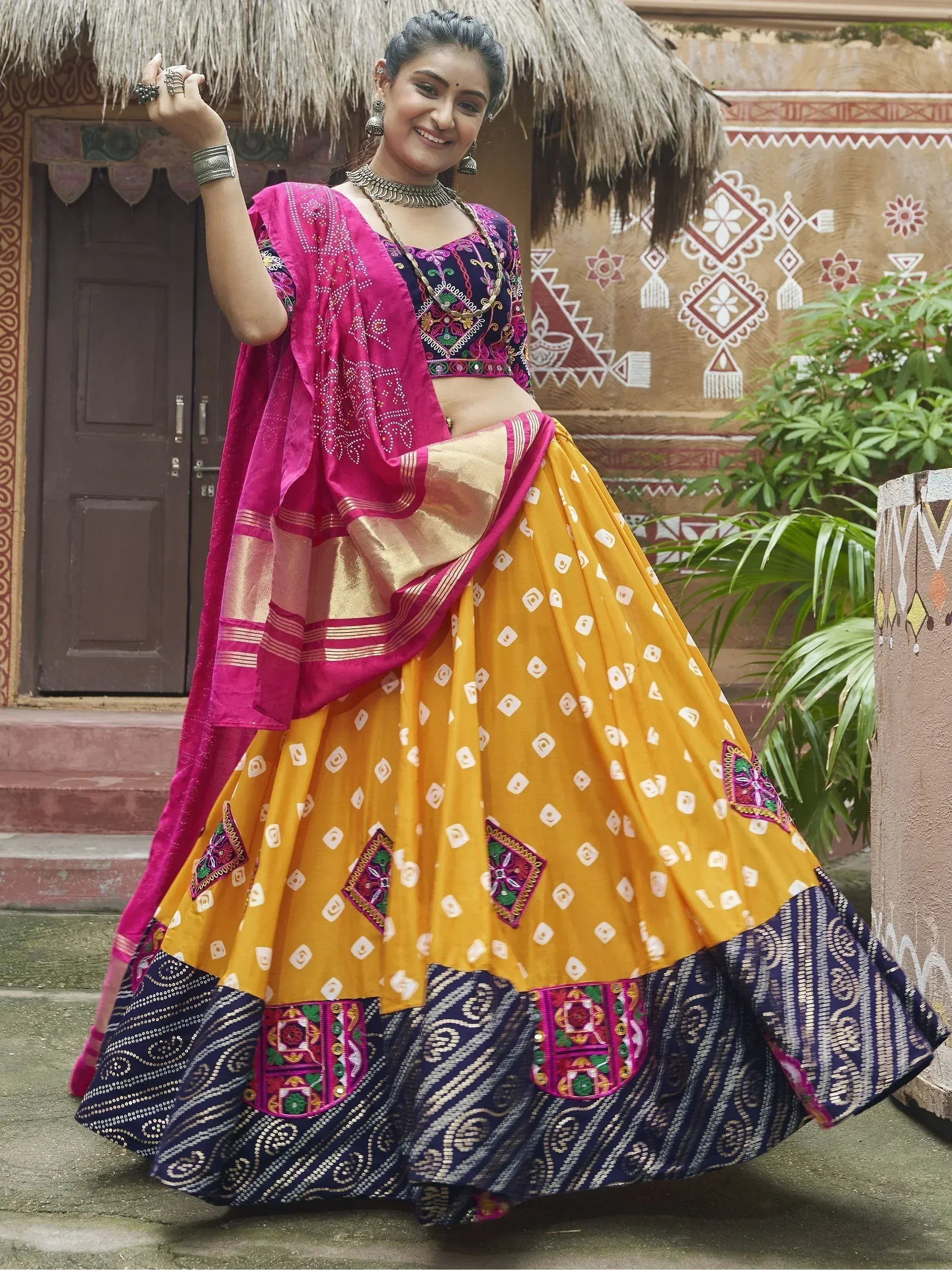 Woman in vibrant yellow and pink embroidered lehenga choli with traditional Indian patterns, perfect for festive occasions.