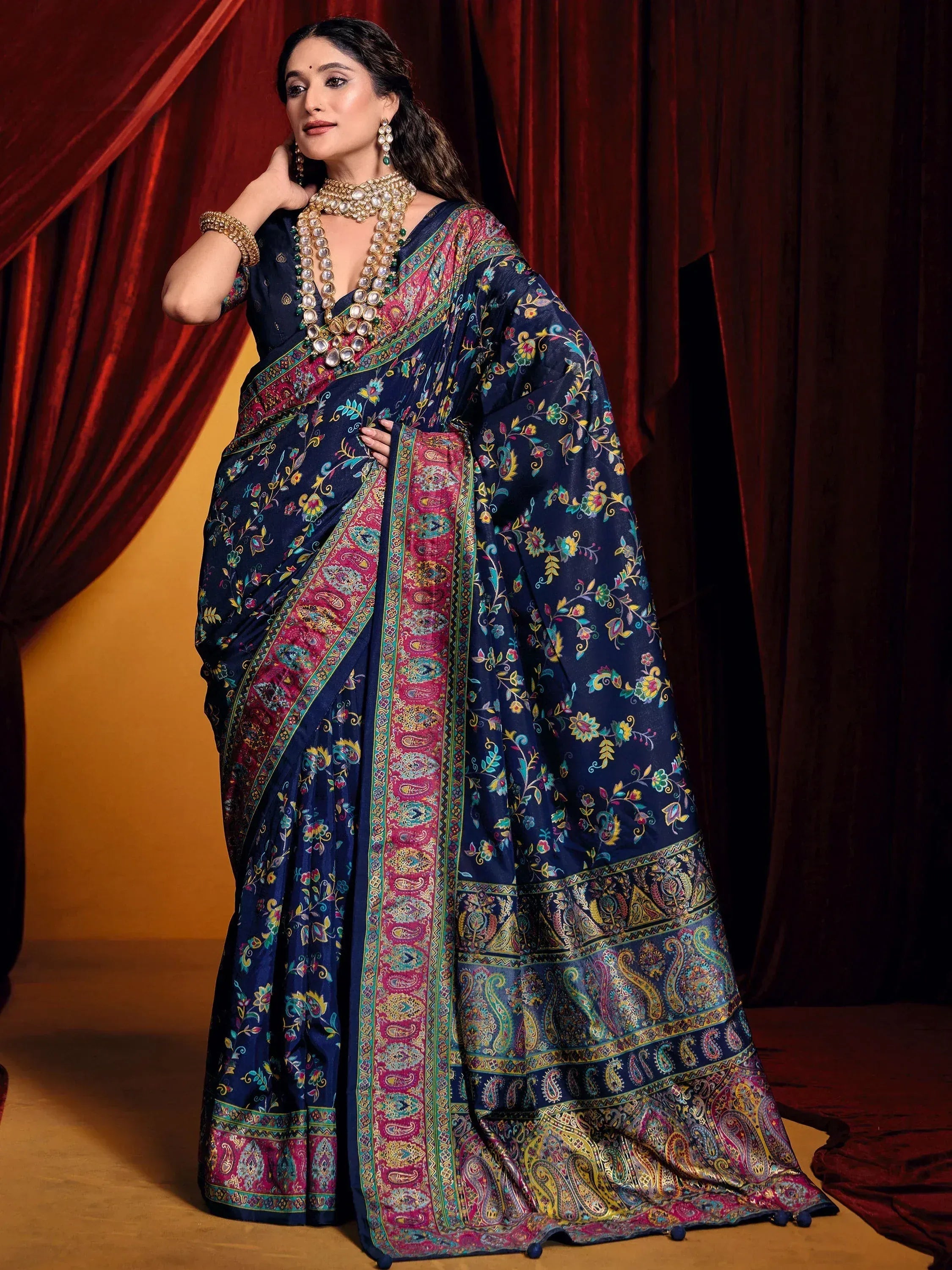 Navy blue floral and paisley printed saree with vibrant border, styled with traditional jewelry for Indian ethnic wear.