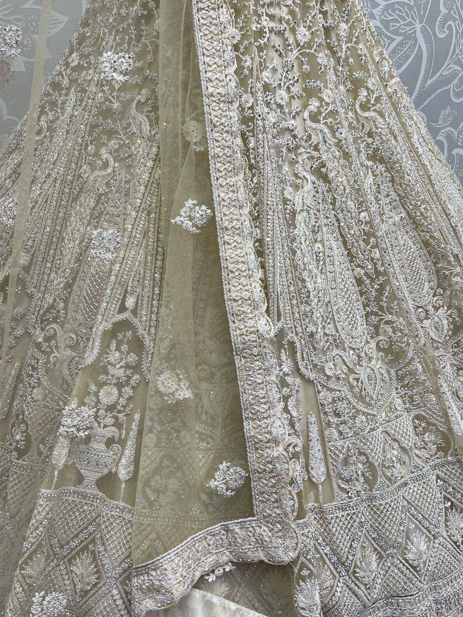 Elegant beige lehenga with intricate silver embroidery and peacock motifs, perfect for Indian weddings.