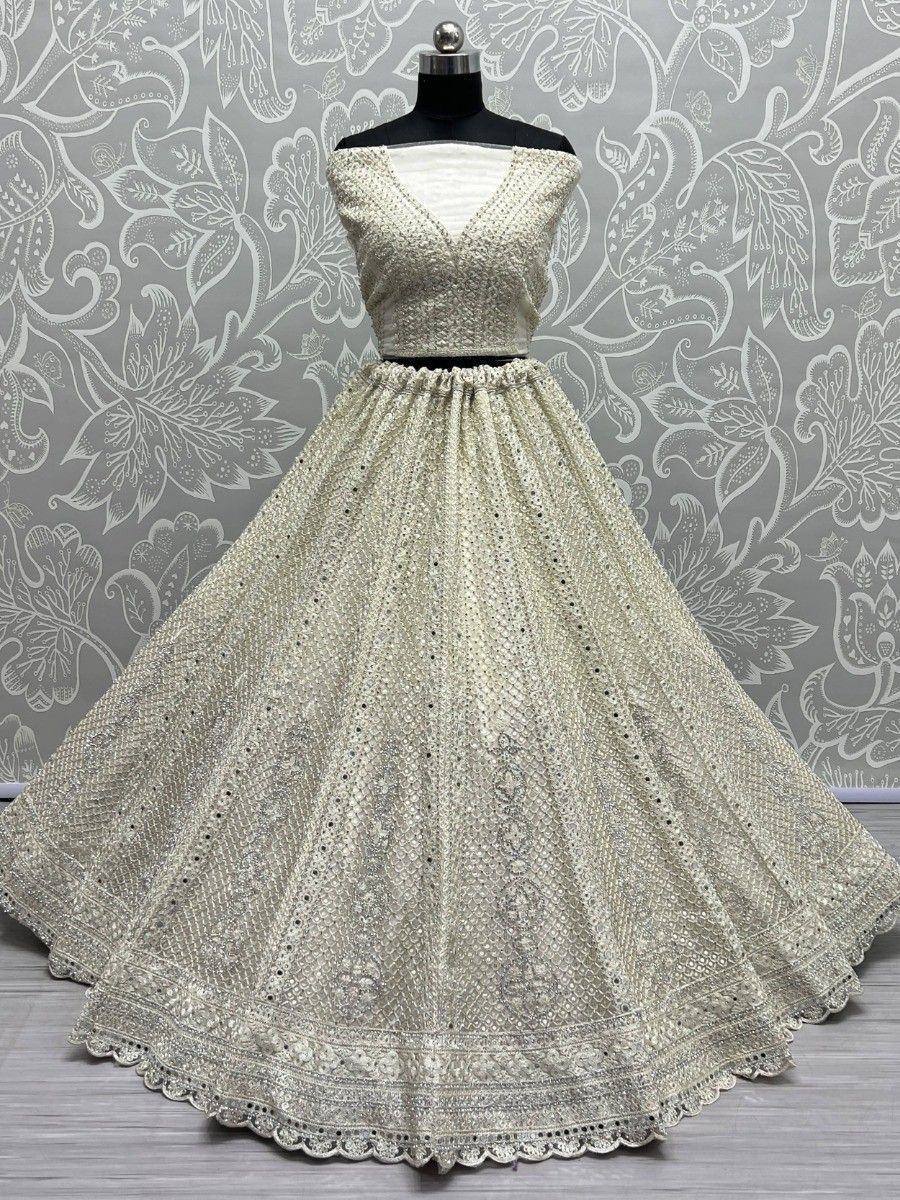 Elegant off-white lehenga choli with intricate embroidery and mirror work, perfect for Indian ethnic occasions.