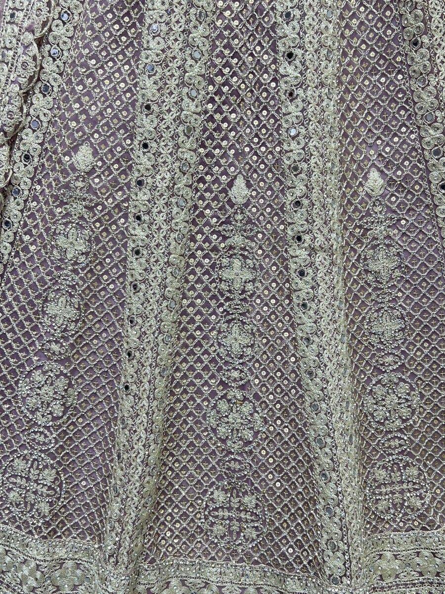 Purple ethnic gown with intricate gold embroidery and mirror work, perfect for Indian weddings and festive occasions.