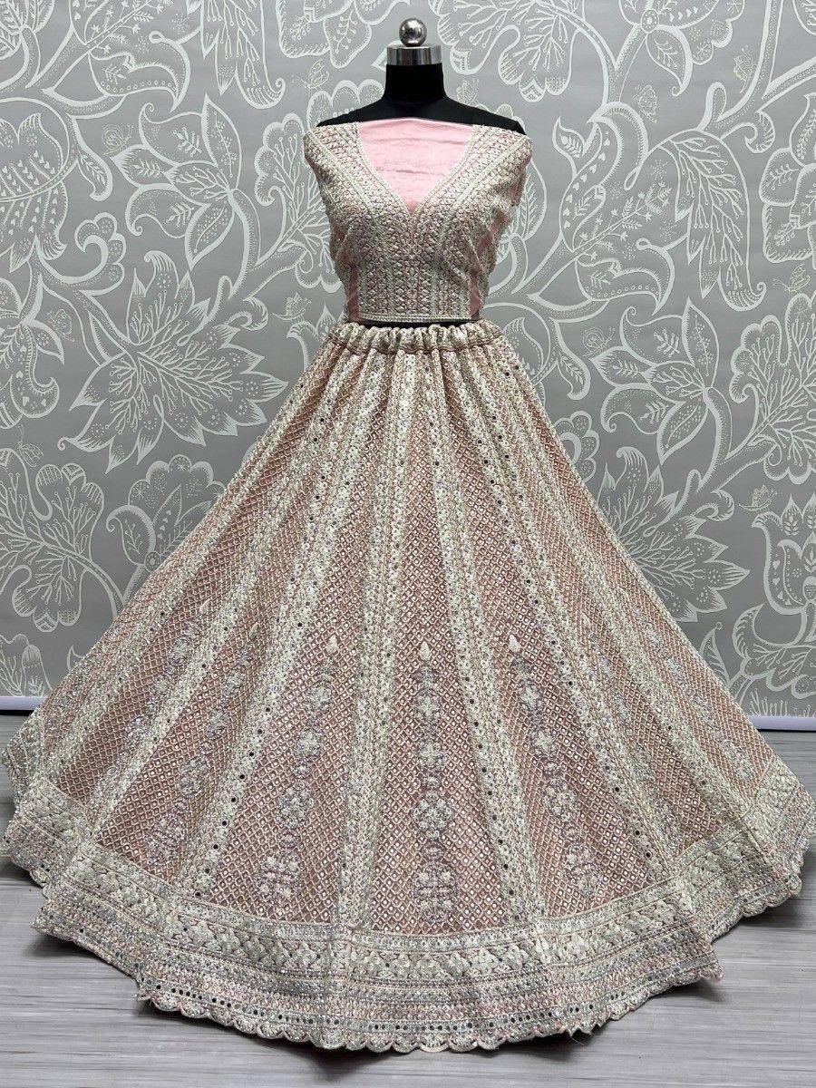 Pink and gold embroidered lehenga choli with intricate mirror work, displayed on mannequin against floral backdrop