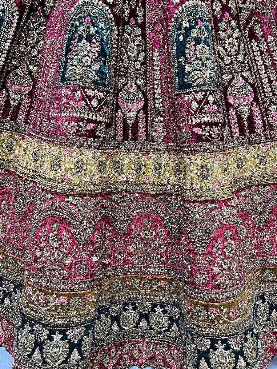 Luxury Indian lehenga with intricate gold embroidery, pink and teal velvet panels, perfect for weddings and festivals.