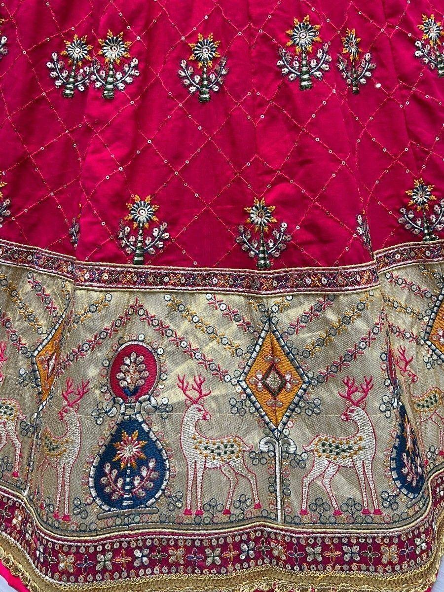 Richly embroidered Indian lehenga with deer motifs, floral patterns, and sequin detailing in red and gold